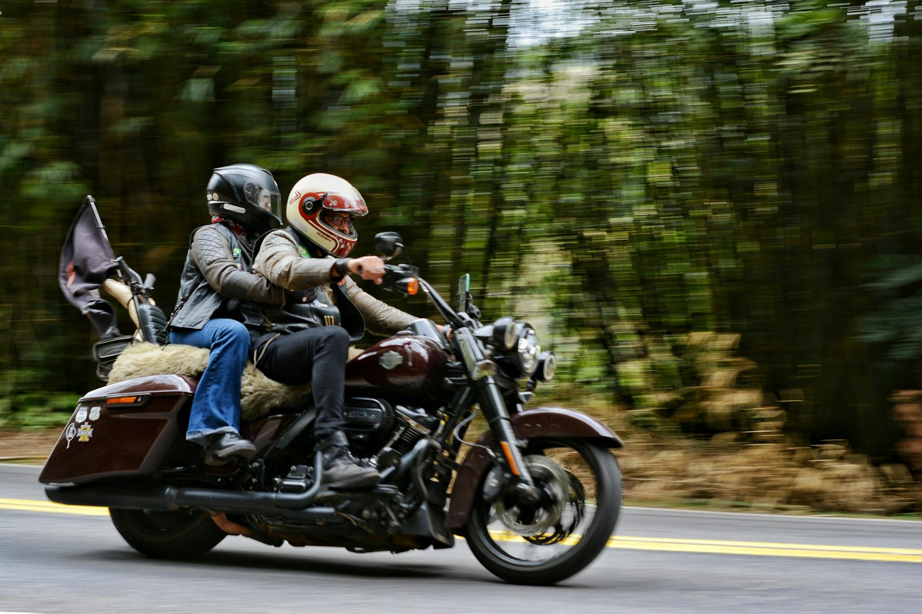 Two bikers ride through Monteiro Lobato's scenic road amidst greenery.