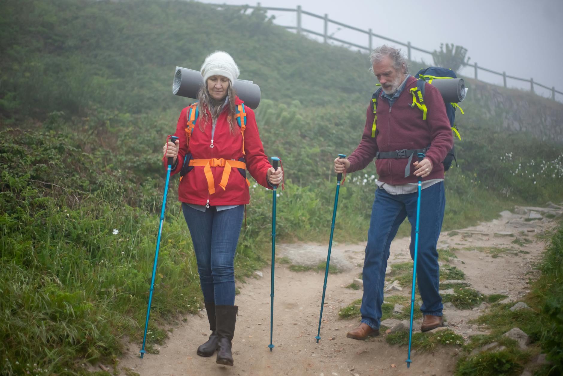 Elderly couple hiking on a foggy trail in Portugal, enjoying nature and adventure.