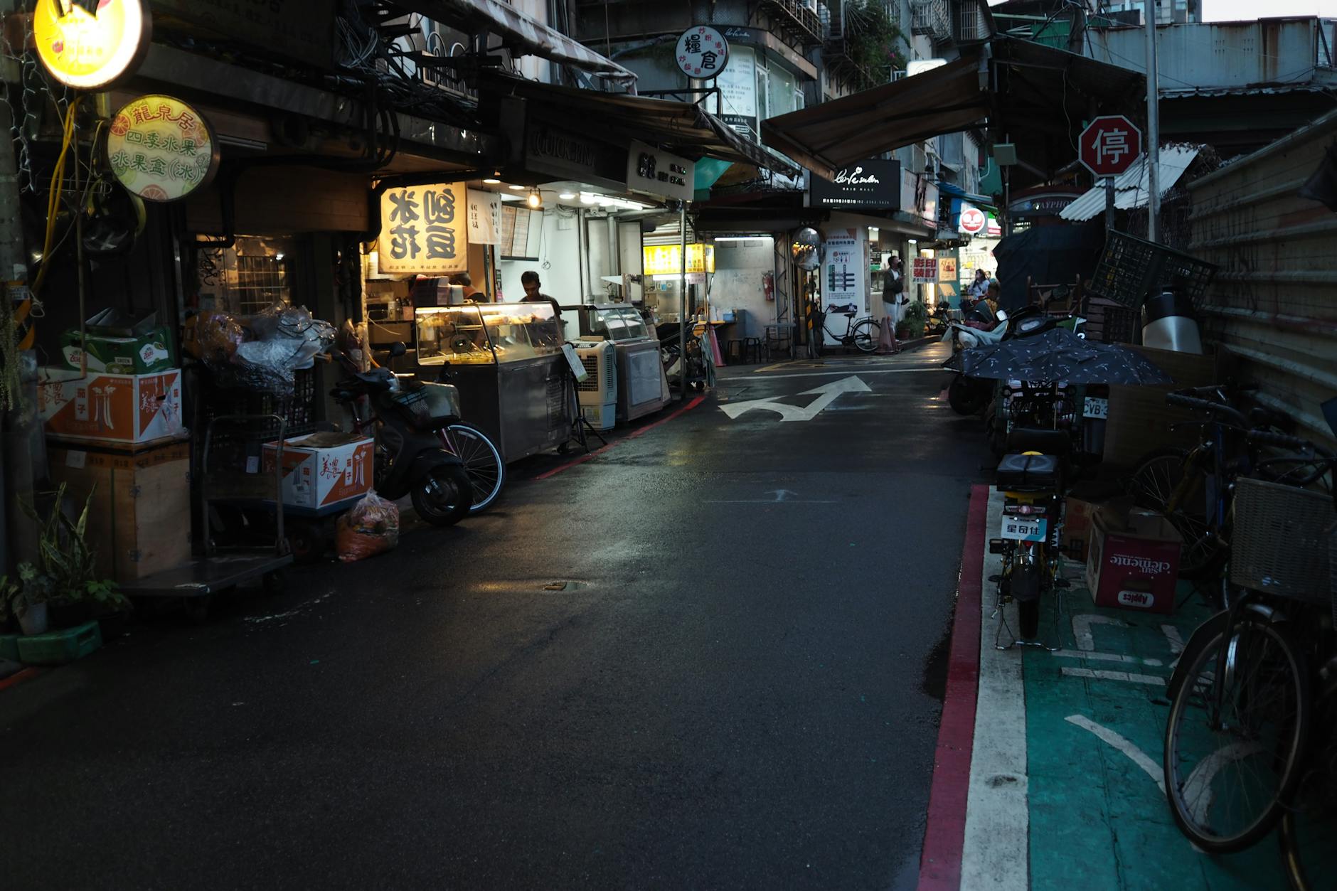 A bustling street with market stalls and neon signs in an Asian city at night.