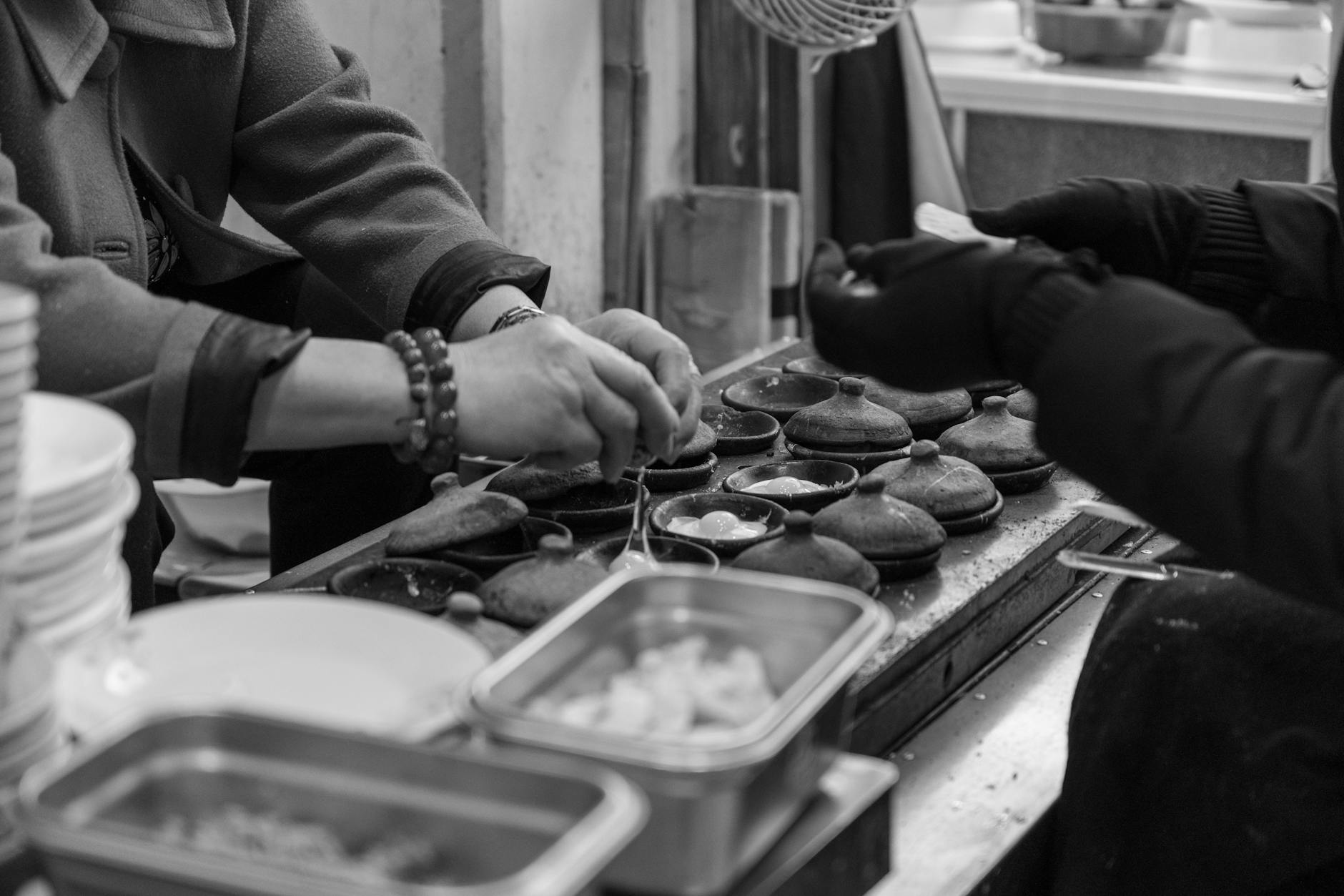 Black and white photo of hands preparing traditional street food in Dalat, Vietnam.