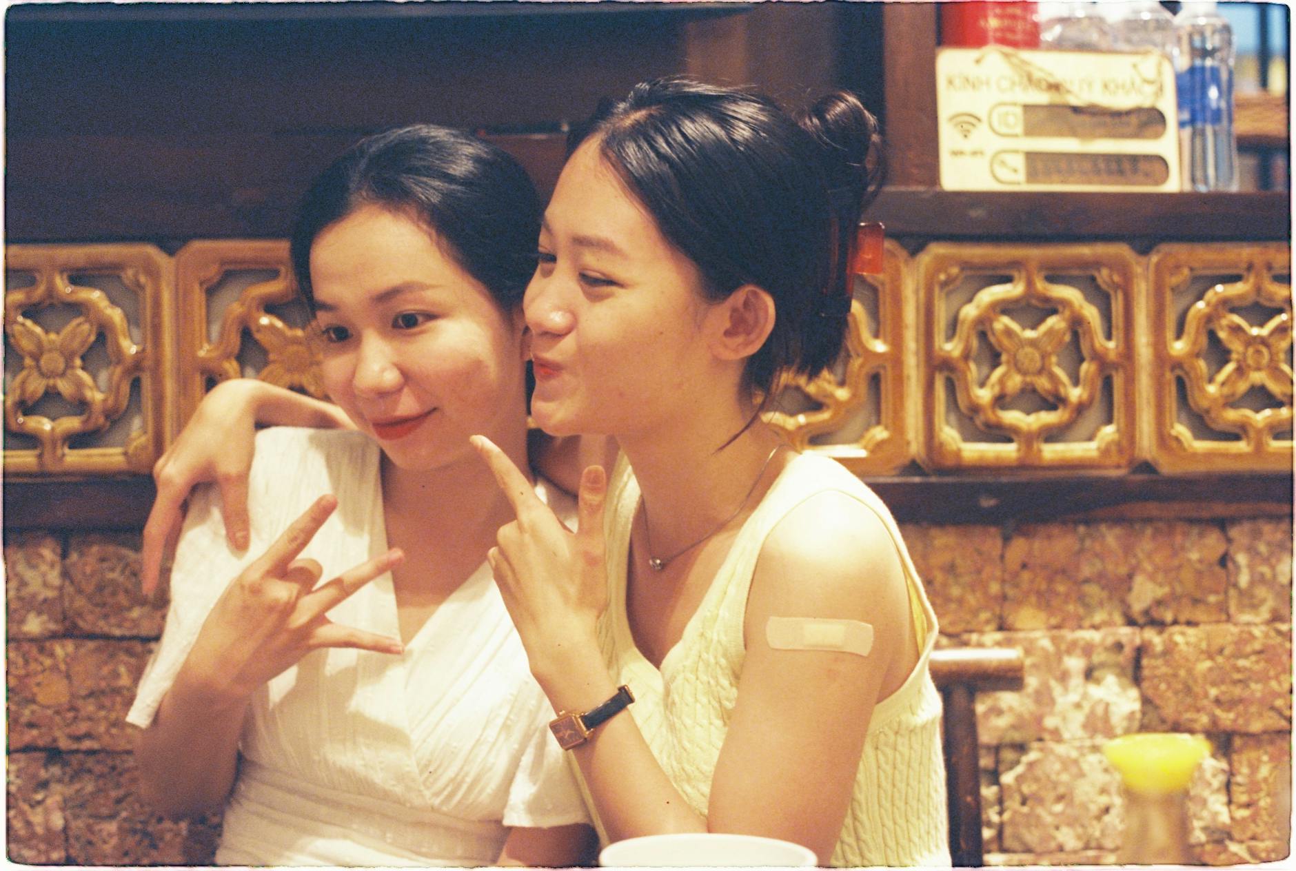Two women sharing a joyful moment in a Ho Chi Minh City restaurant, showcasing friendship.