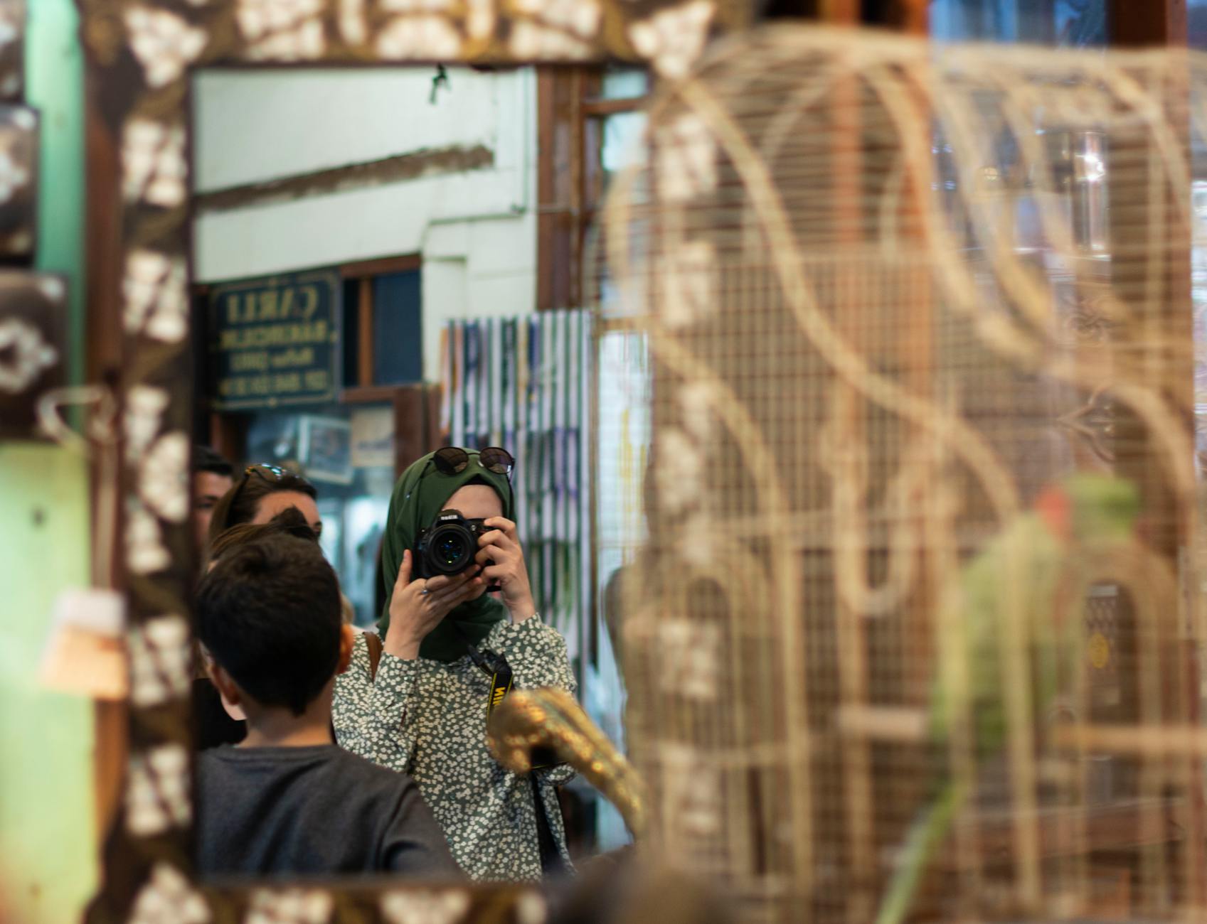 Reflection photo of a woman in hijab capturing a moment in a Turkish bazaar.