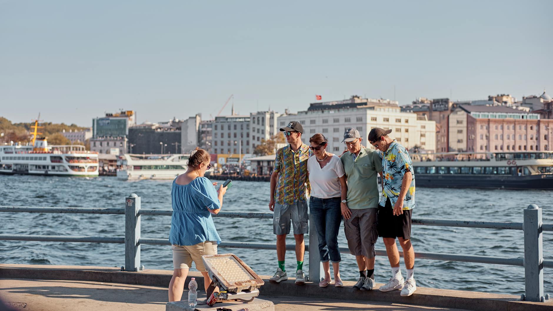 A family poses for a photo by the Bosphorus in İstanbul, capturing a memorable moment.
