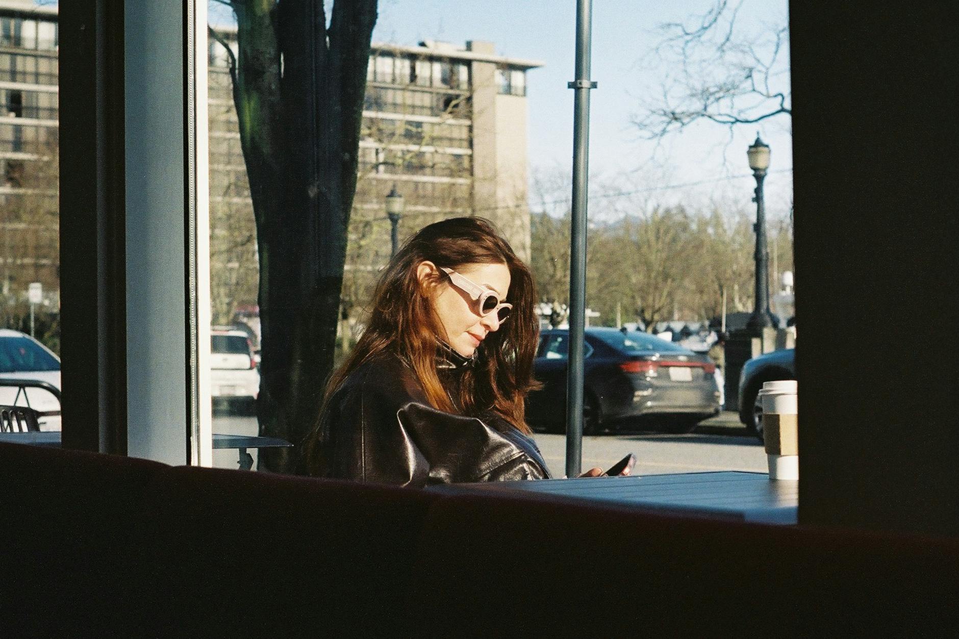 Woman enjoying morning coffee and sunlight in a Vancouver cafe, embracing a modern urban lifestyle.