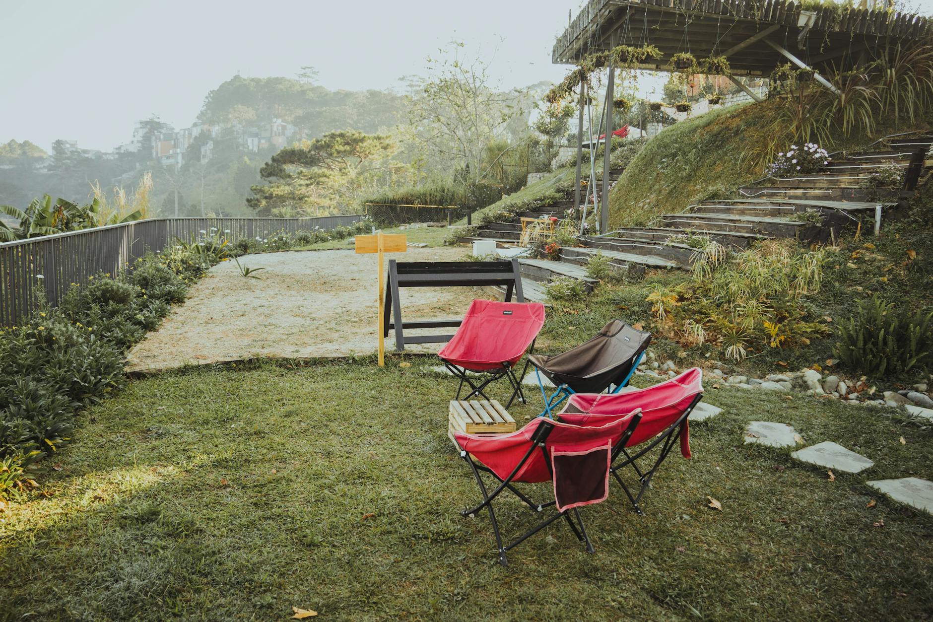 A serene garden setting with colorful chairs and scenic misty hills, perfect for a peaceful retreat.