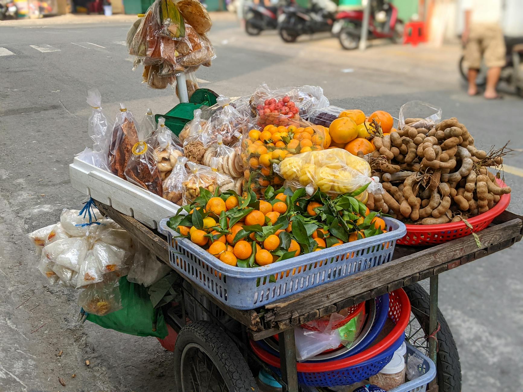 Colorful street food cart in Hue, featuring fresh citrus and tamarind.