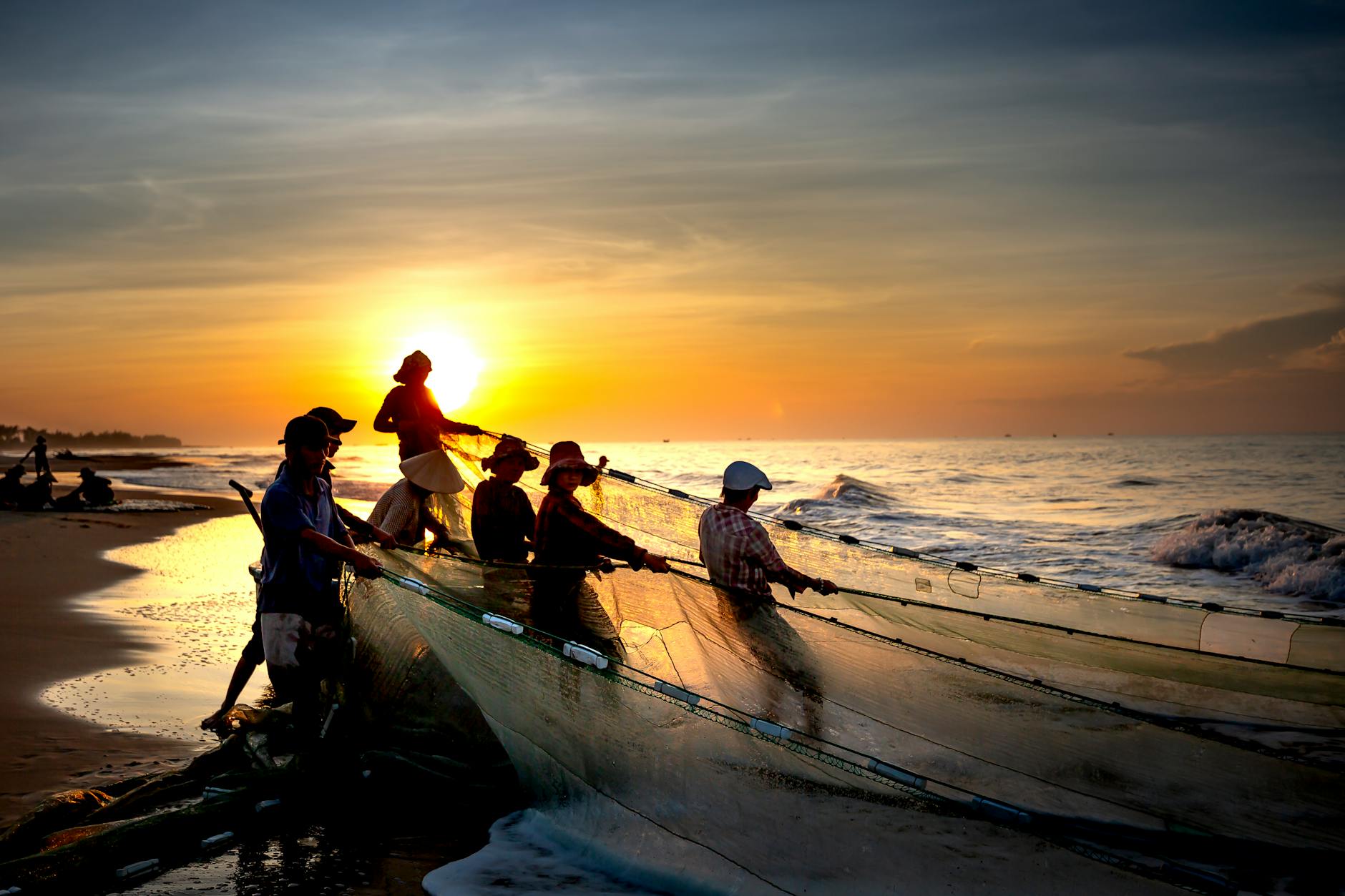 Fishermen pulling nets at sunrise in La Gi, Vietnam, capturing a vibrant seascape.
