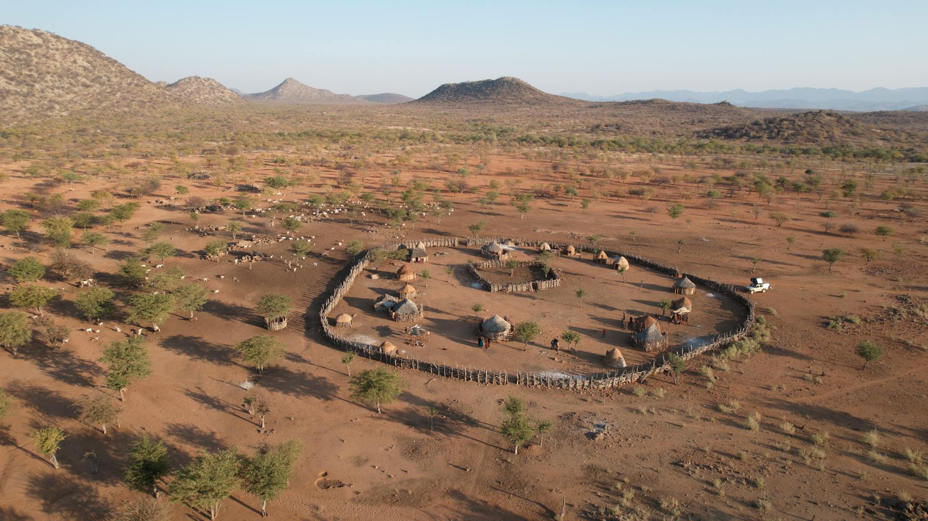 Aerial view of a traditional village in Namibia surrounded by a vast desert landscape.