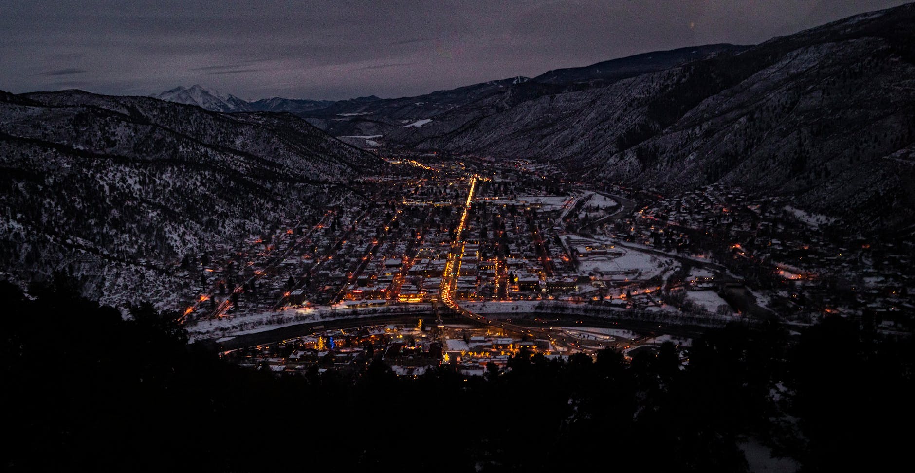 Captivating aerial night view of Glenwood Springs, CO in winter, highlighting urban lights.