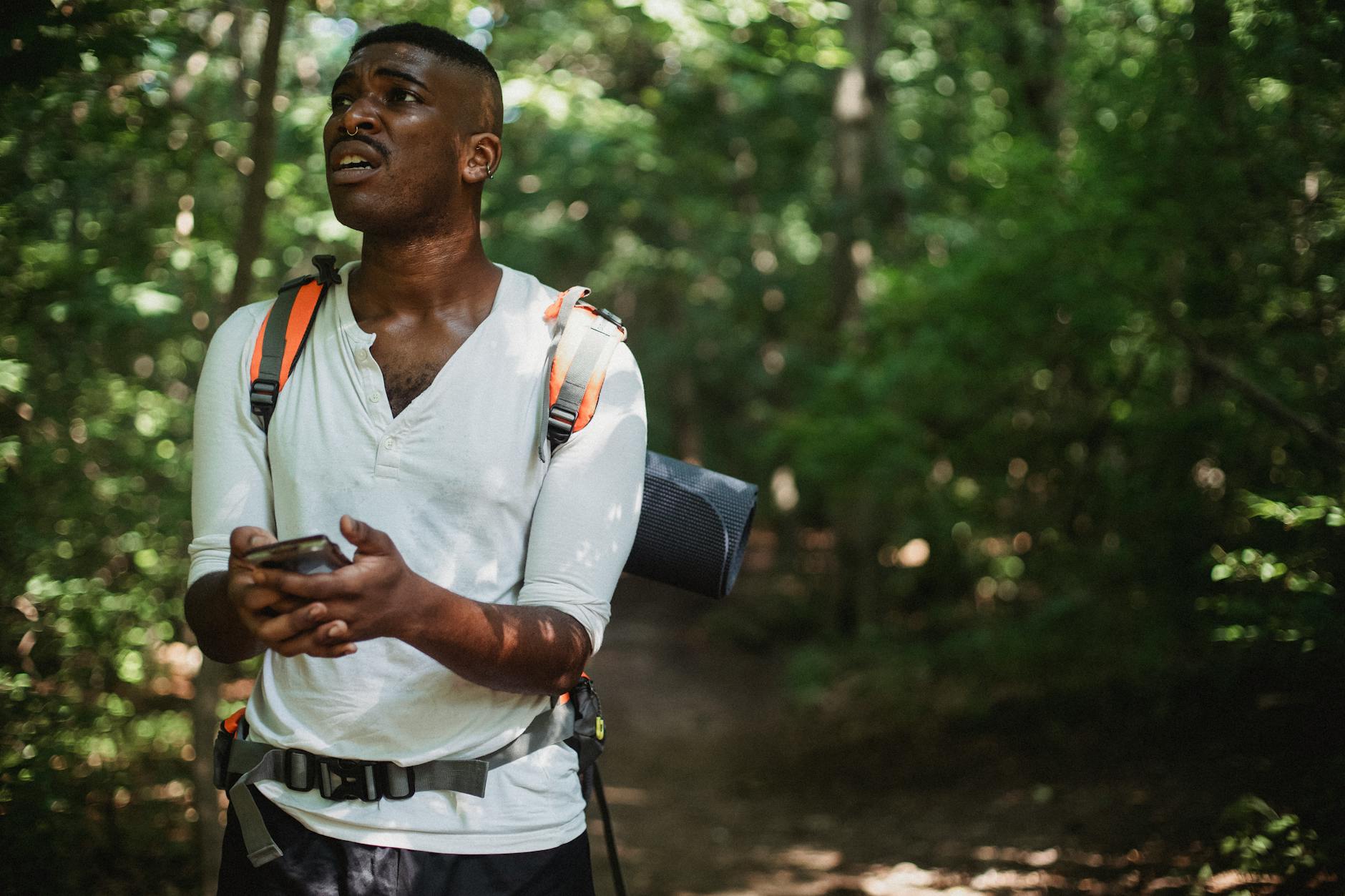 African American male with backpack lost GPS signal while using mobile phone and hiking in woods