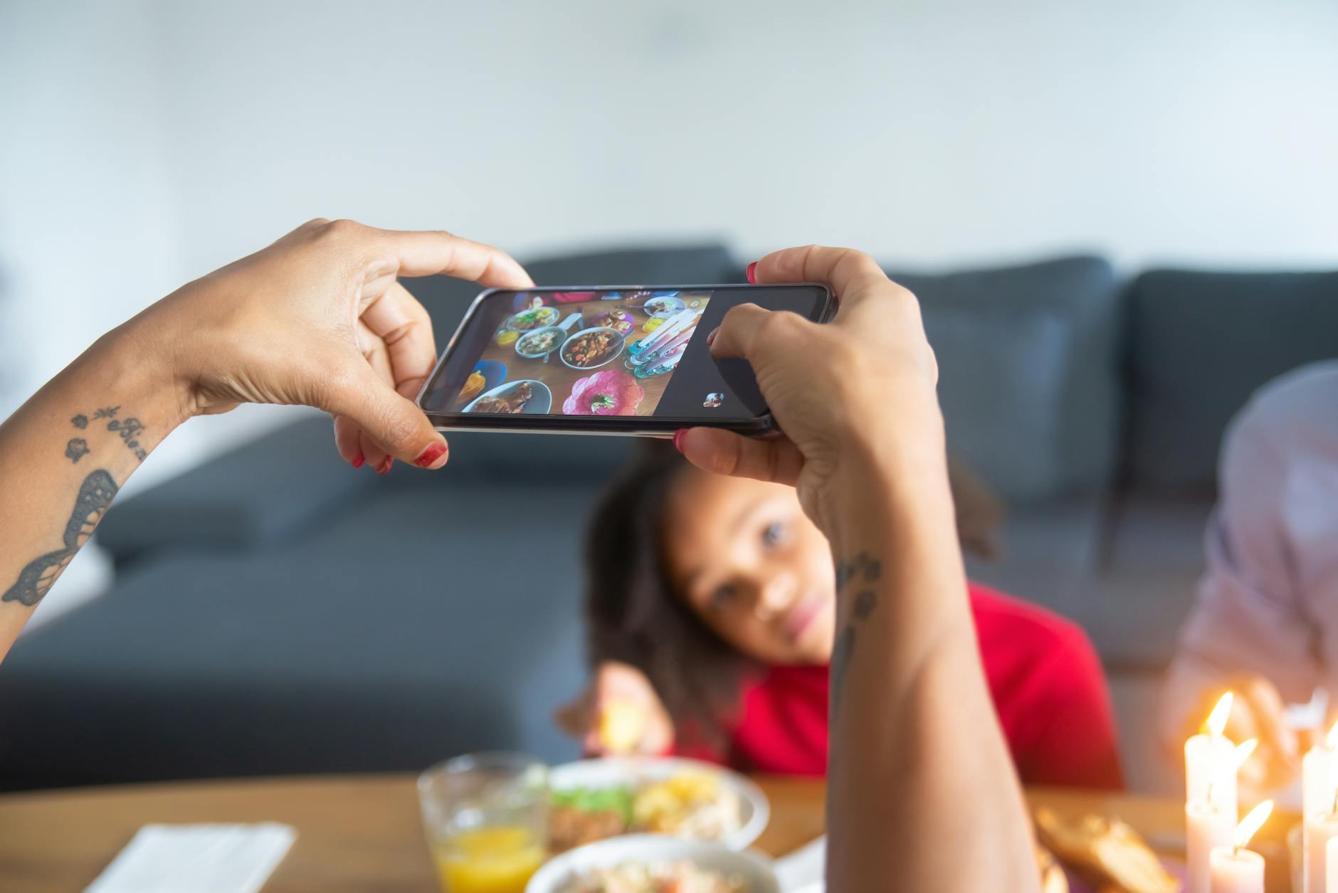 A family enjoys a meal as a woman takes a photo with her smartphone indoors.
