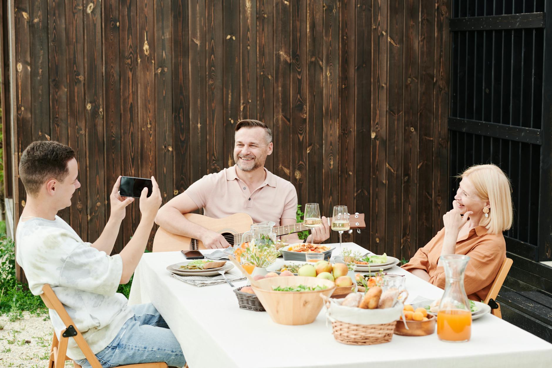 A family enjoying a meal outdoors with music and laughter, capturing precious moments together.