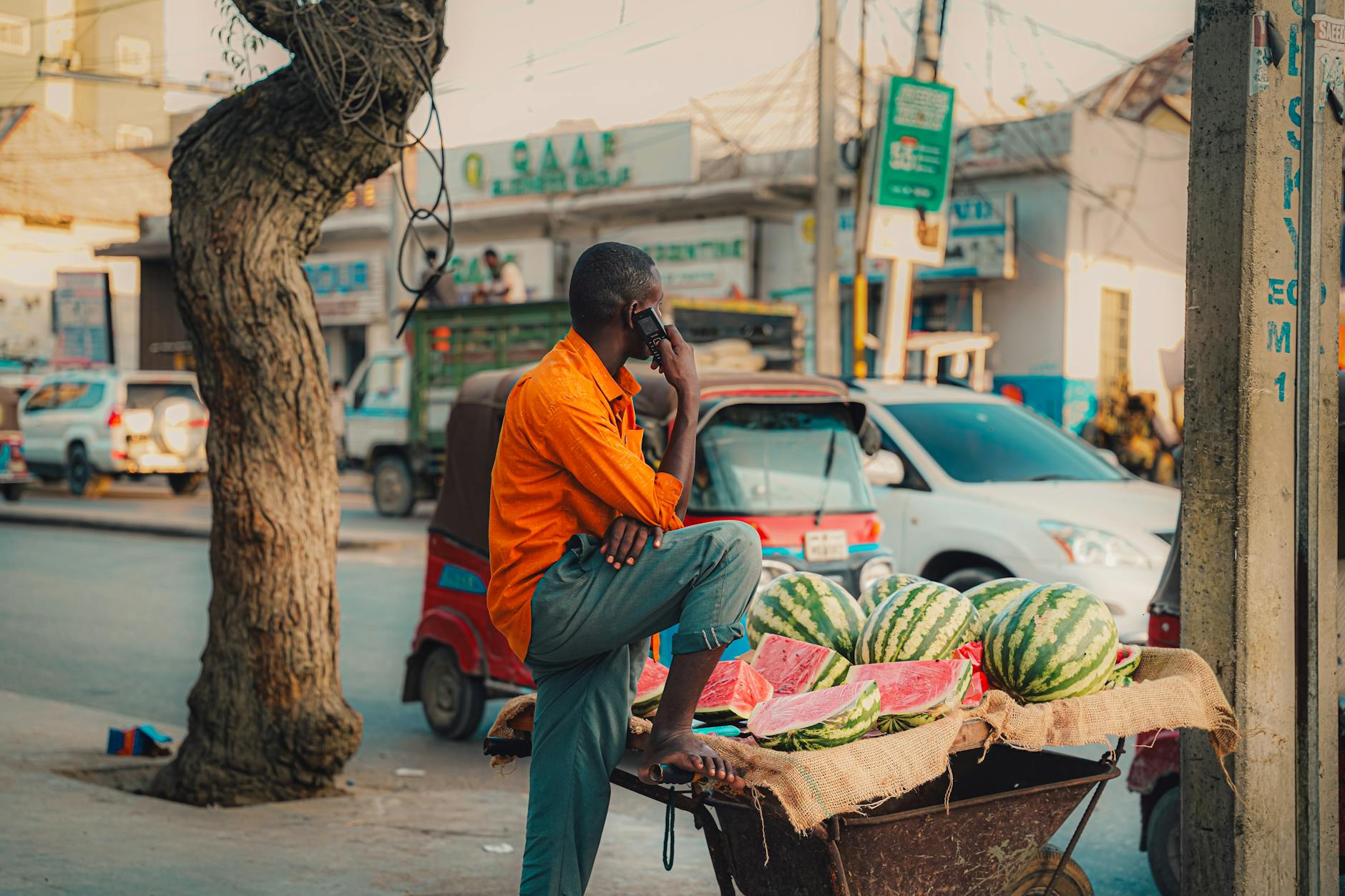 A street vendor in Mogadishu sells watermelons while speaking on the phone.