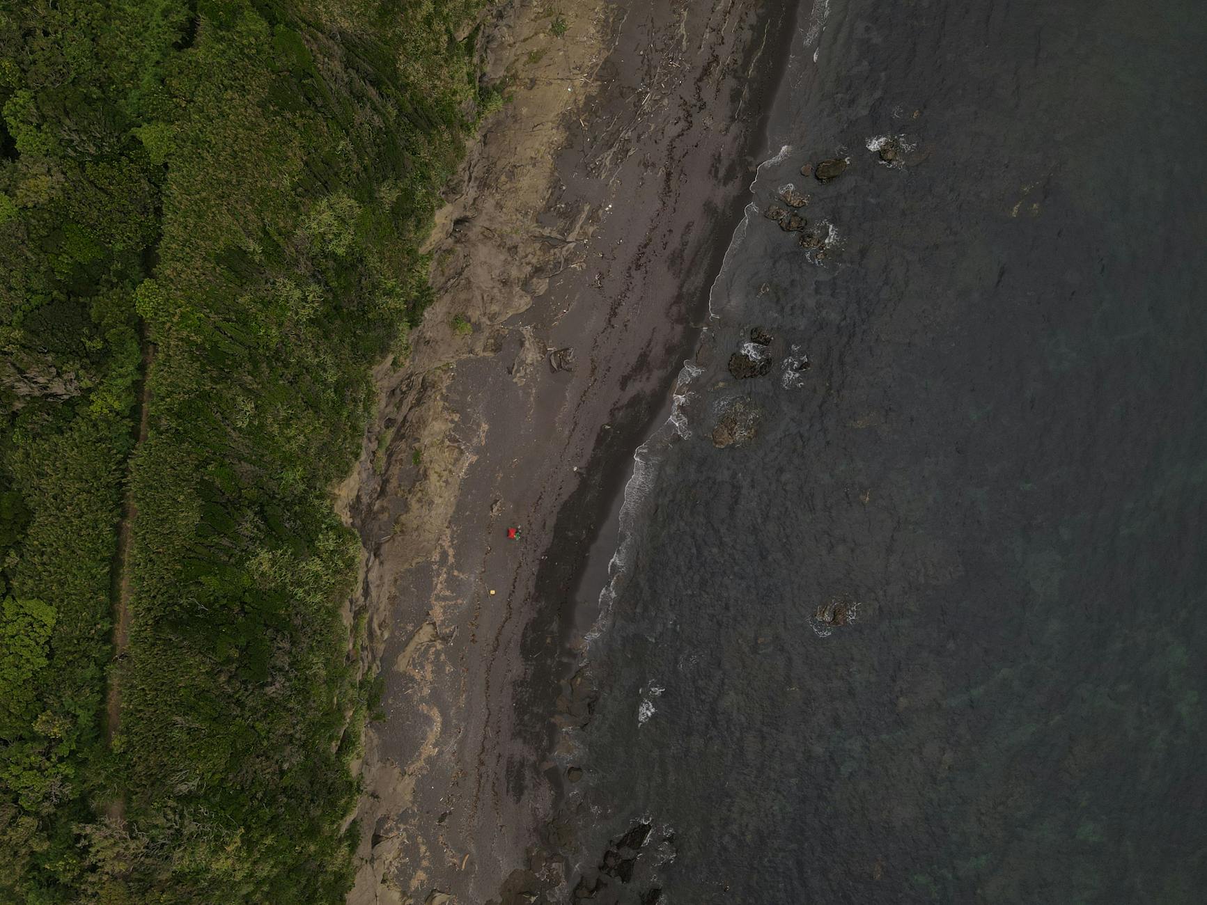 Drone shot of a secluded Miura beach with lush greenery and tranquil waters.