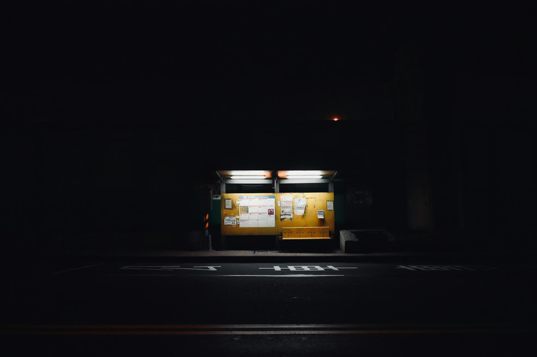 Atmospheric nighttime shot of an empty city bus stop with illuminated signage.