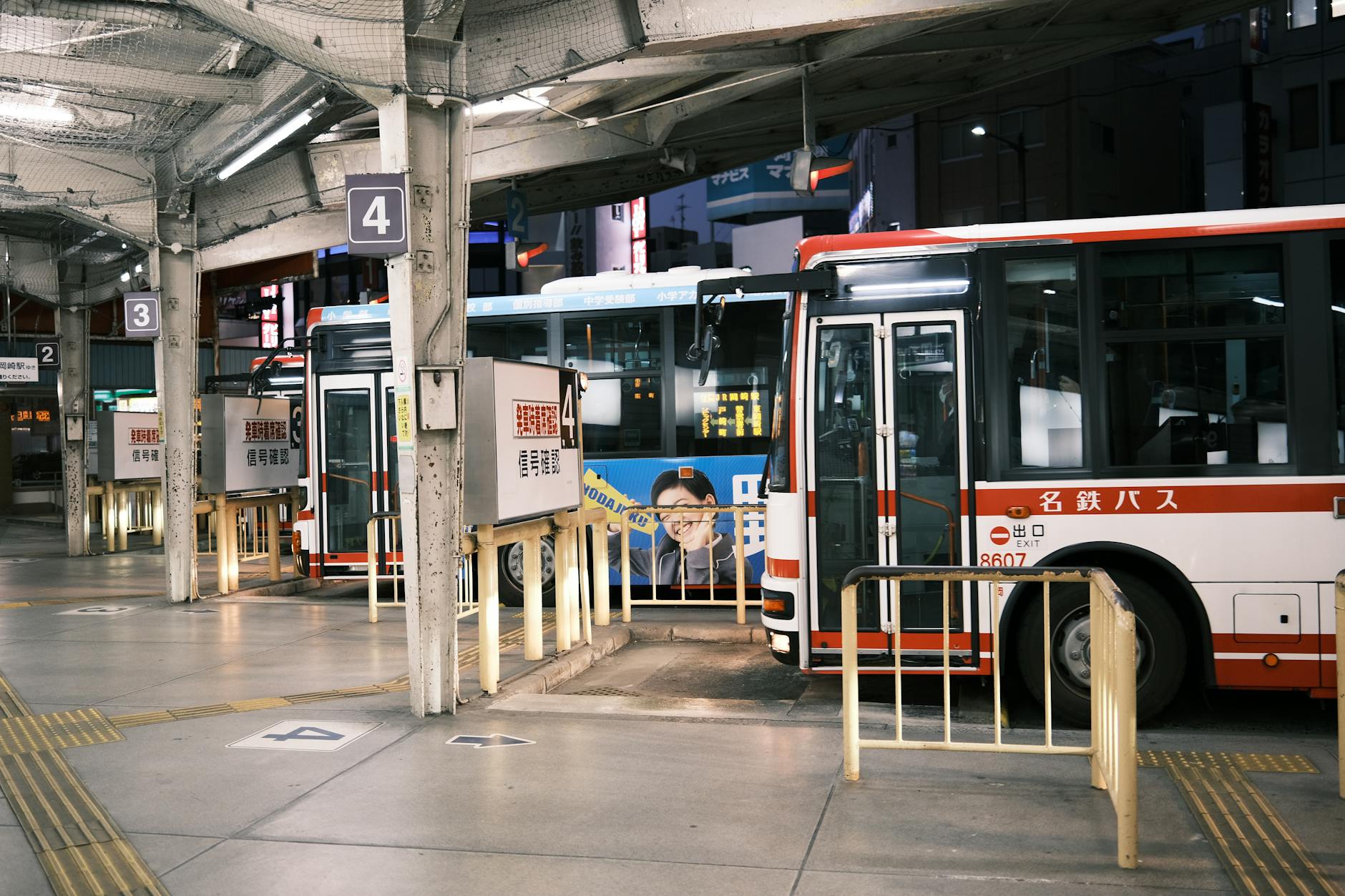 A bustling bus station in Okazaki, Aichi, Japan at night, showcasing lined buses.