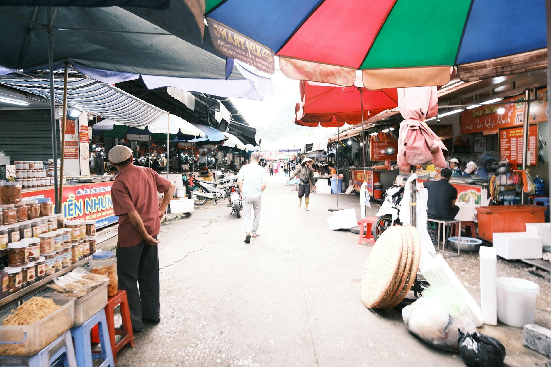Bustling street market with colorful umbrellas and diverse foods, capturing a lively day scene.