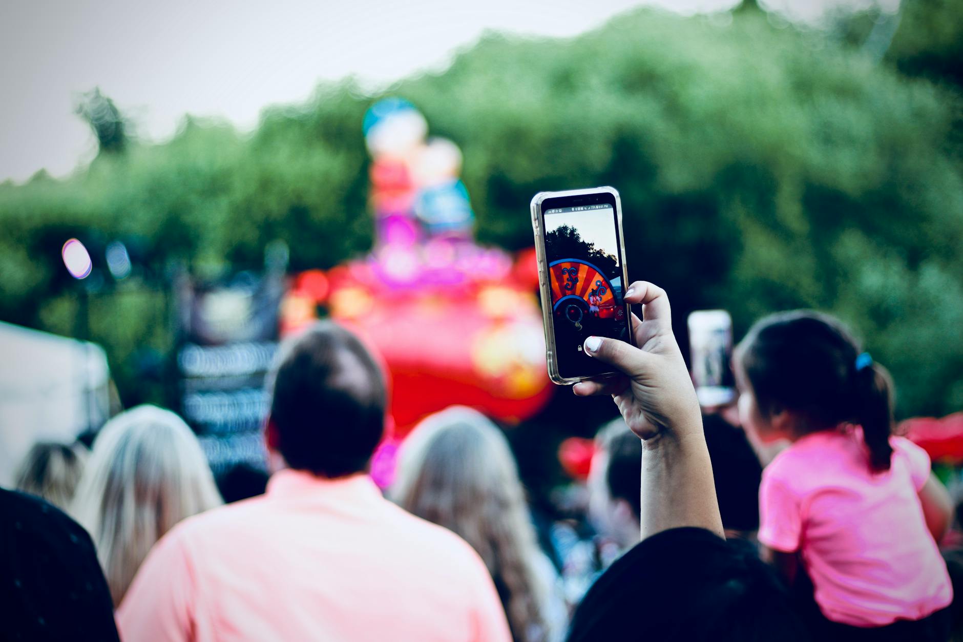 A lively festival scene with a crowd enjoying and capturing moments with smartphones.