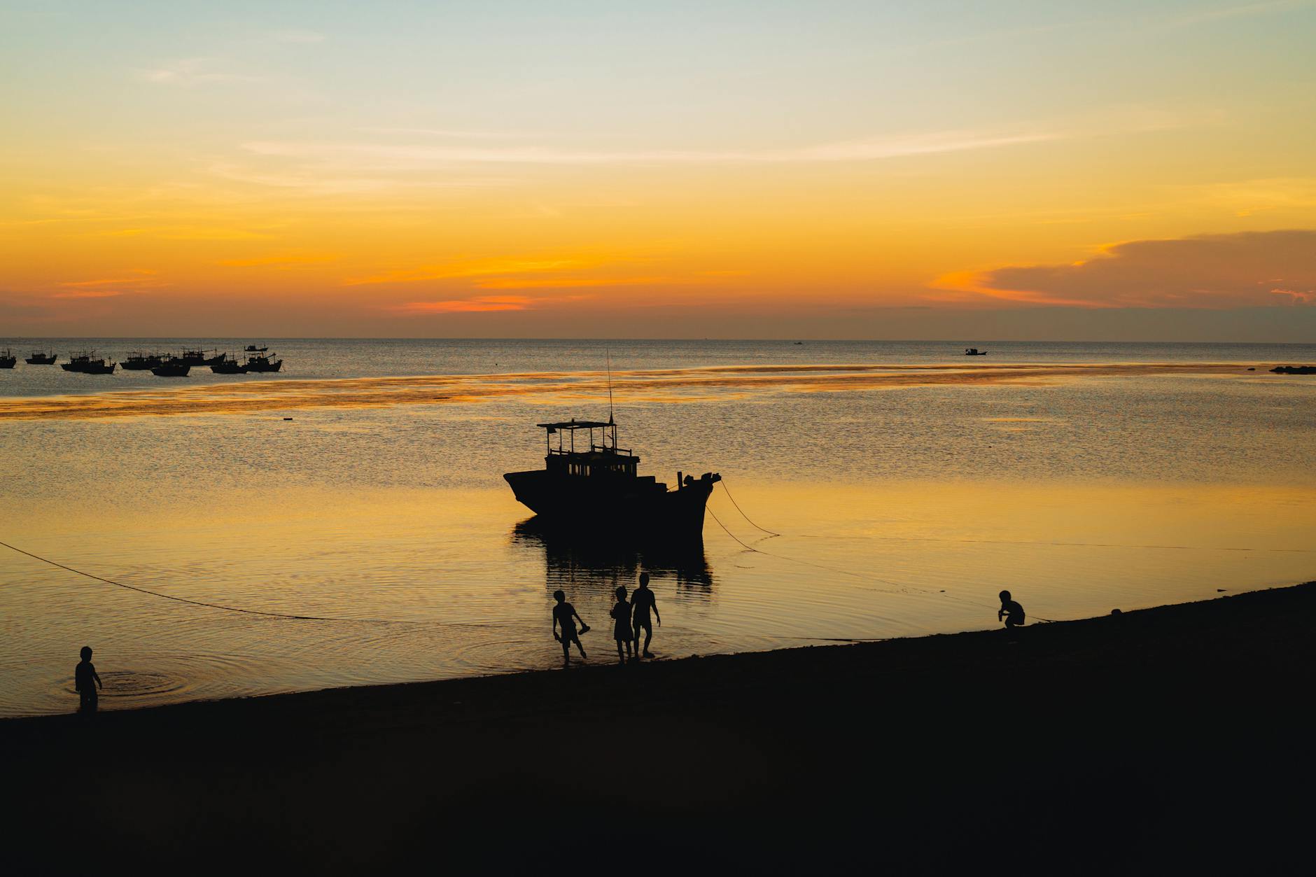 Captivating sunset view at a Vietnamese beach with silhouettes of people and boats.
