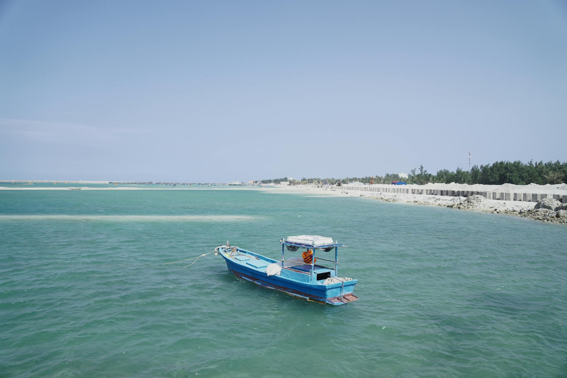 A tranquil blue boat floats on the turquoise waters of Phan Thiet, Vietnam, ideal for summer travel.