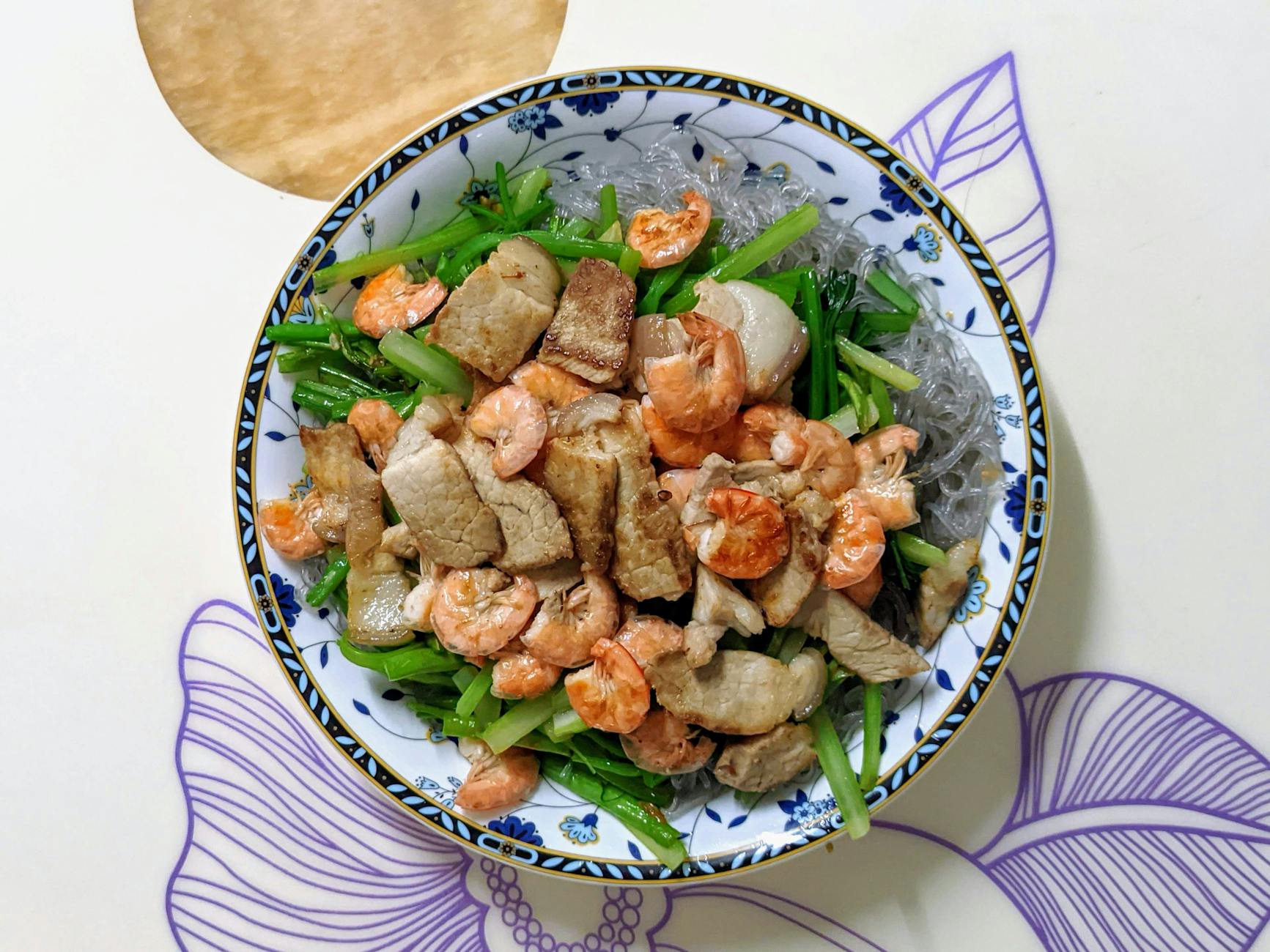 Appetizing Vietnamese rice noodle dish with shrimp and pork, showcasing vibrant and fresh ingredients.