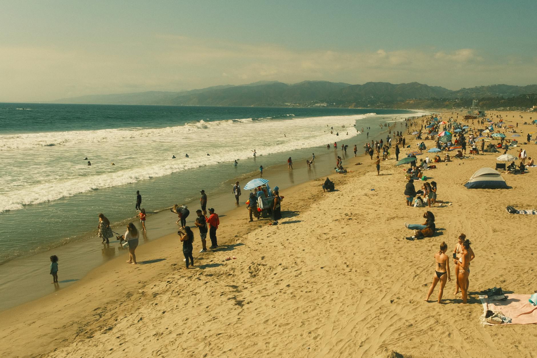 A vibrant scene at Santa Monica Beach with people enjoying a sunny day in Los Angeles.
