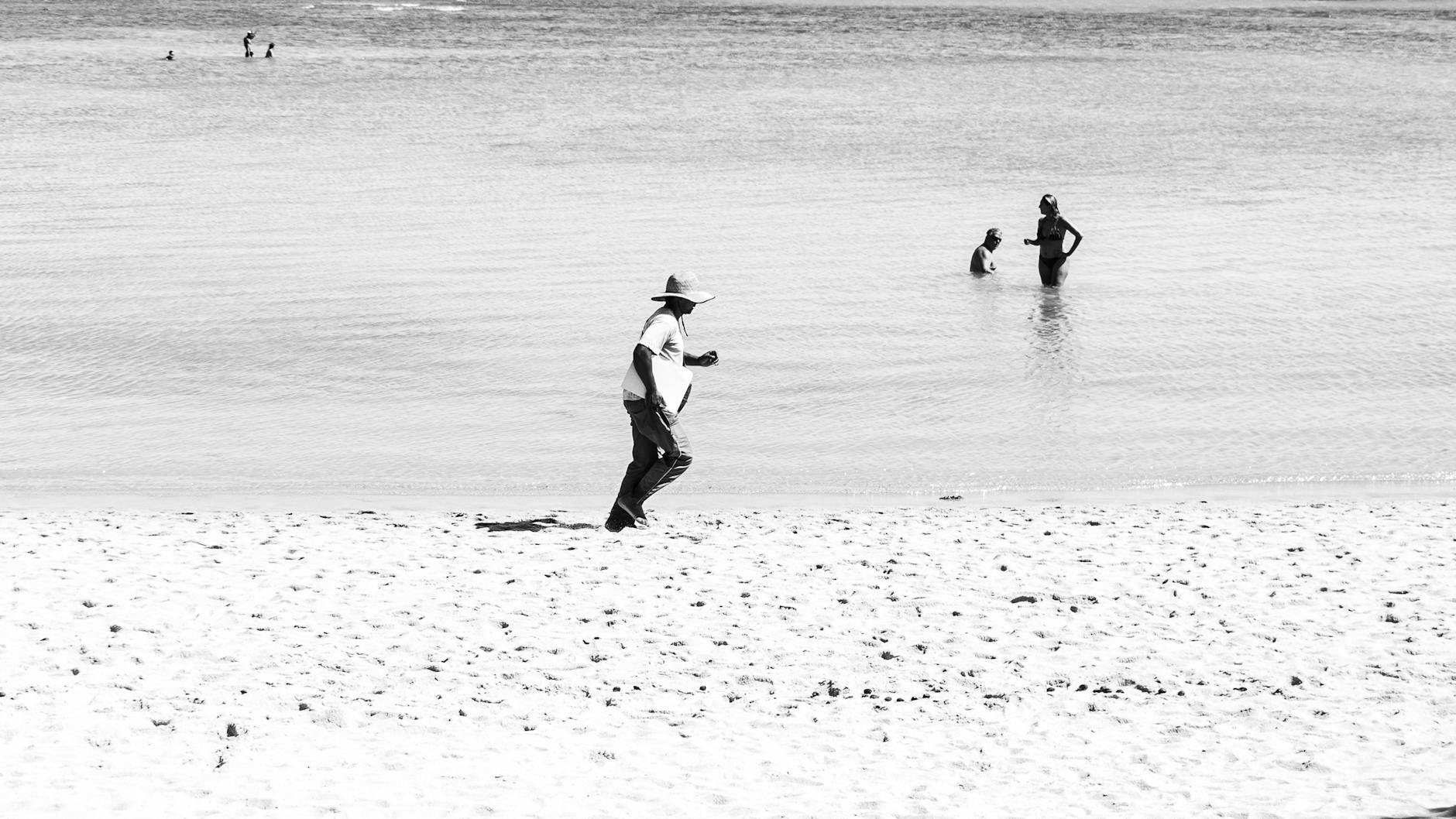 A monochrome beach scene in Porto Seguro, Brazil with people enjoying the water and sand.