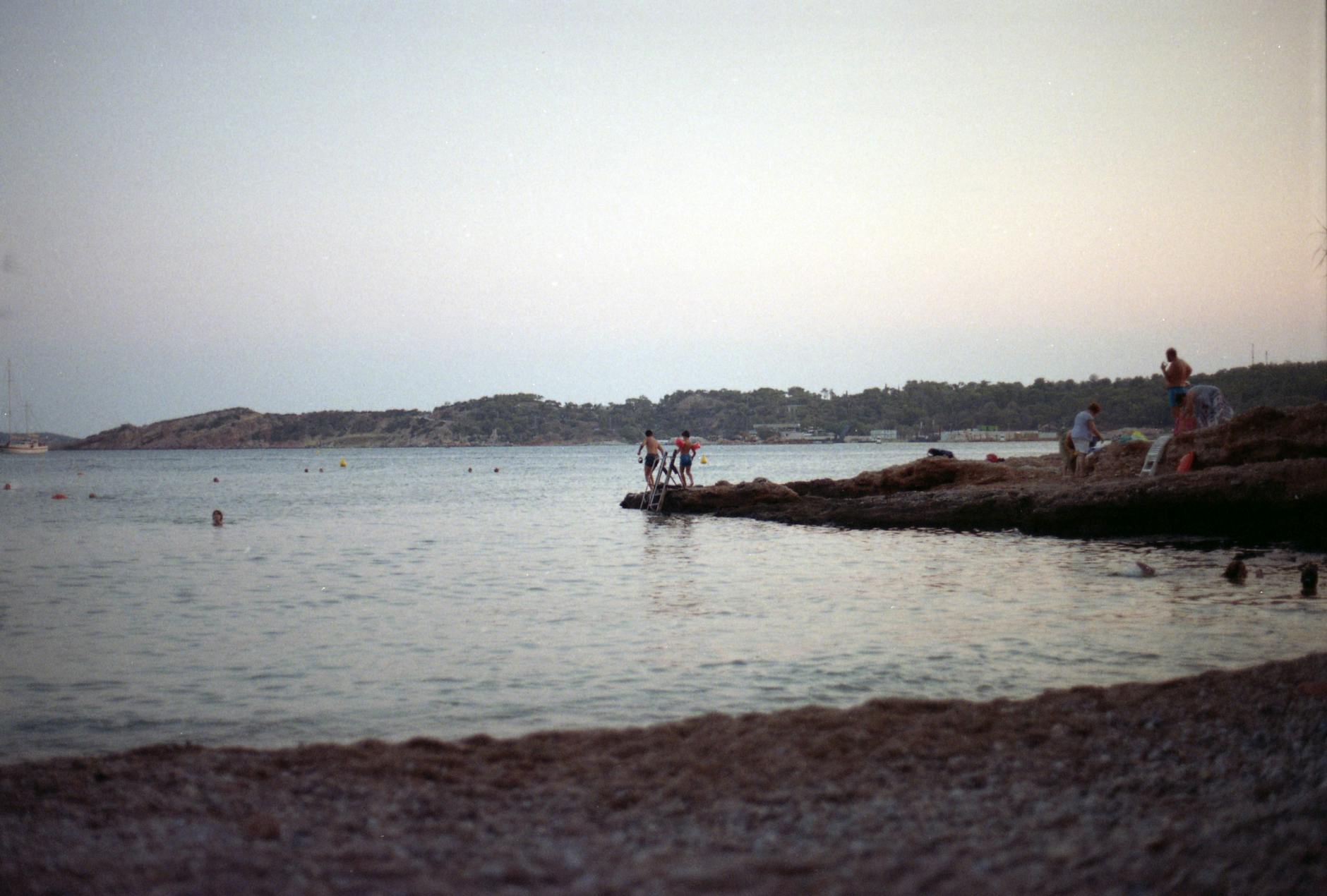 People enjoying a serene summer sunset by the sea in Athens, Greece.