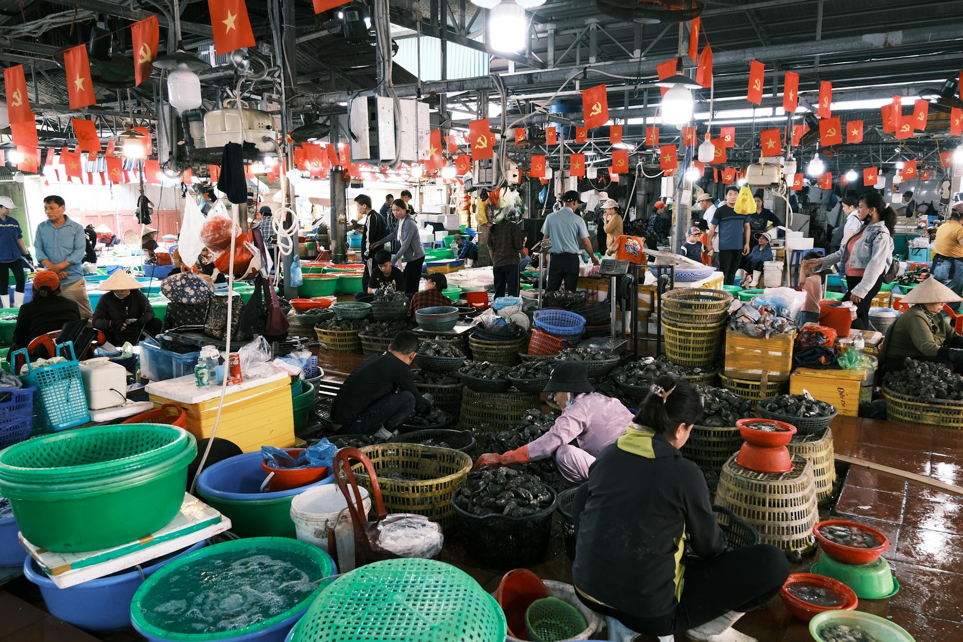 Crowded indoor seafood market in Vietnam with local vendors and colorful baskets.
