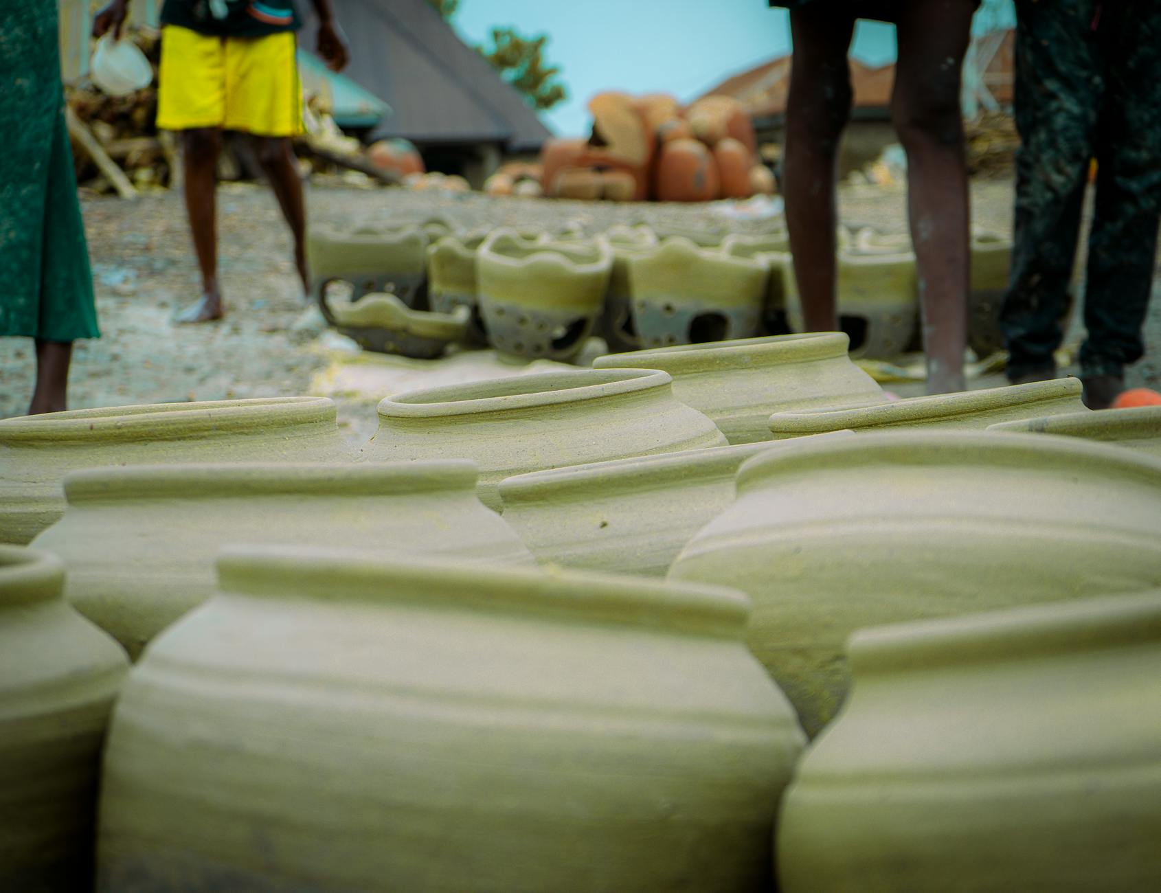 Handcrafted pottery in rural village with people. Traditional methods showcased in outdoor setting.