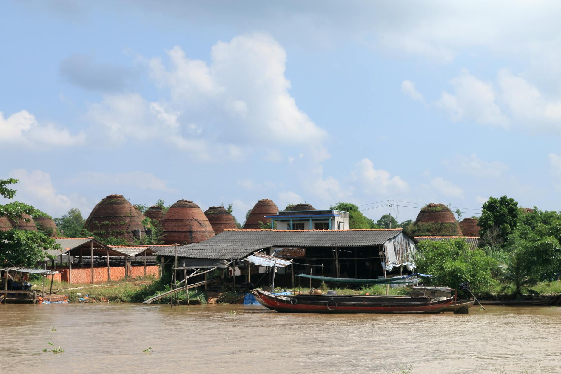 Traditional pottery kilns beside a river, under a clear sky in Vietnam.