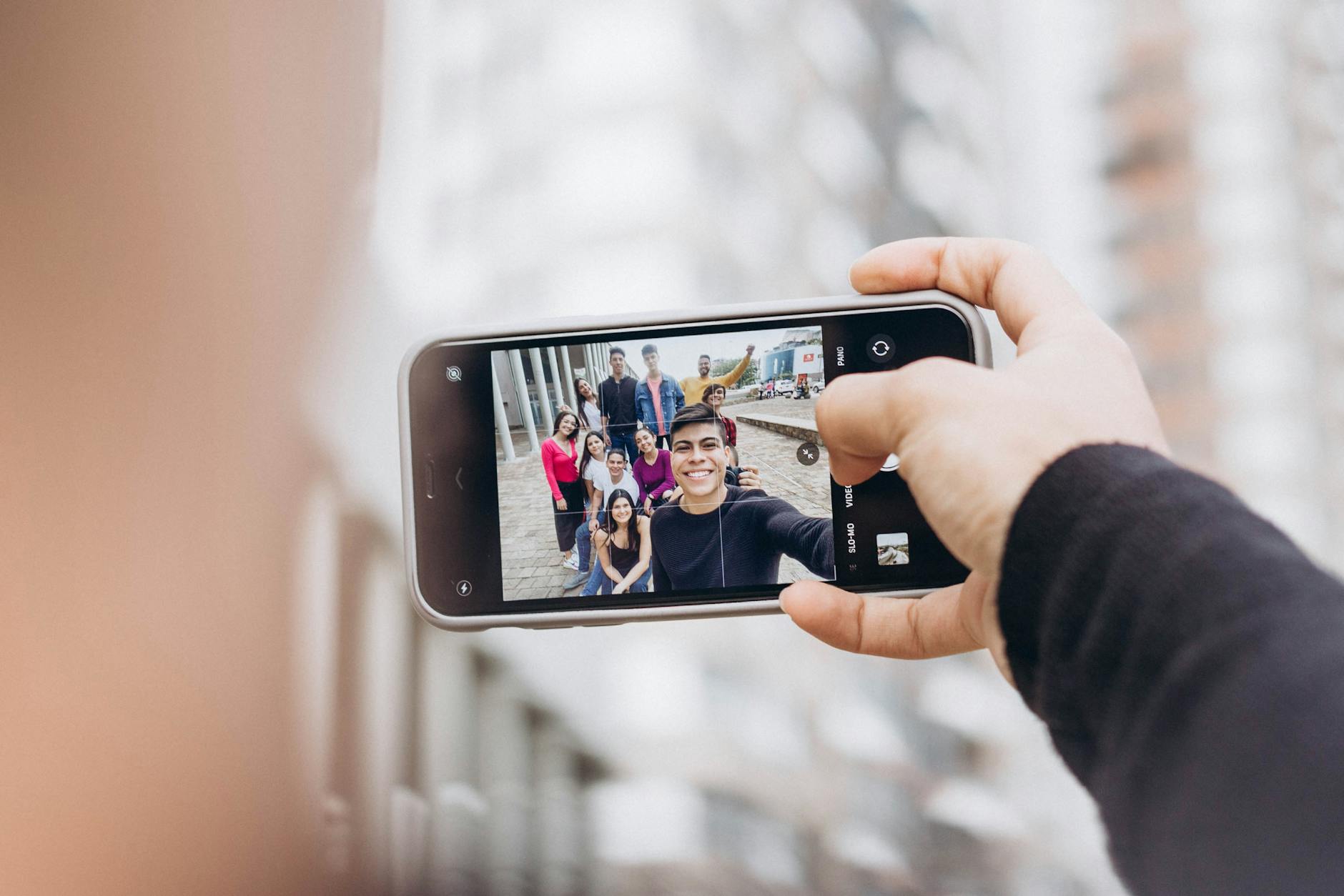 A group of friends taking a selfie with a smartphone on the streets of New York City.