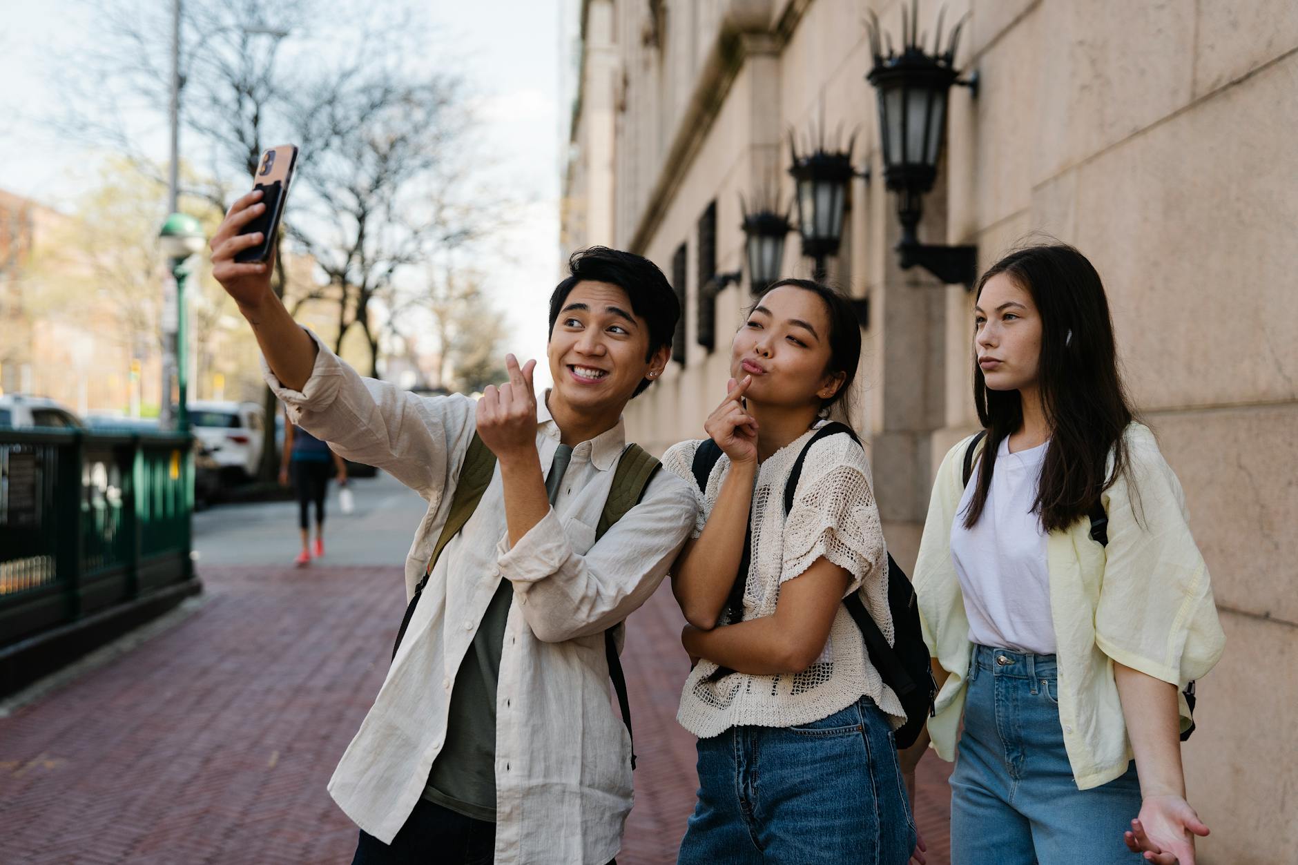 A group of young adults enjoying a selfie together on a city street during the day.