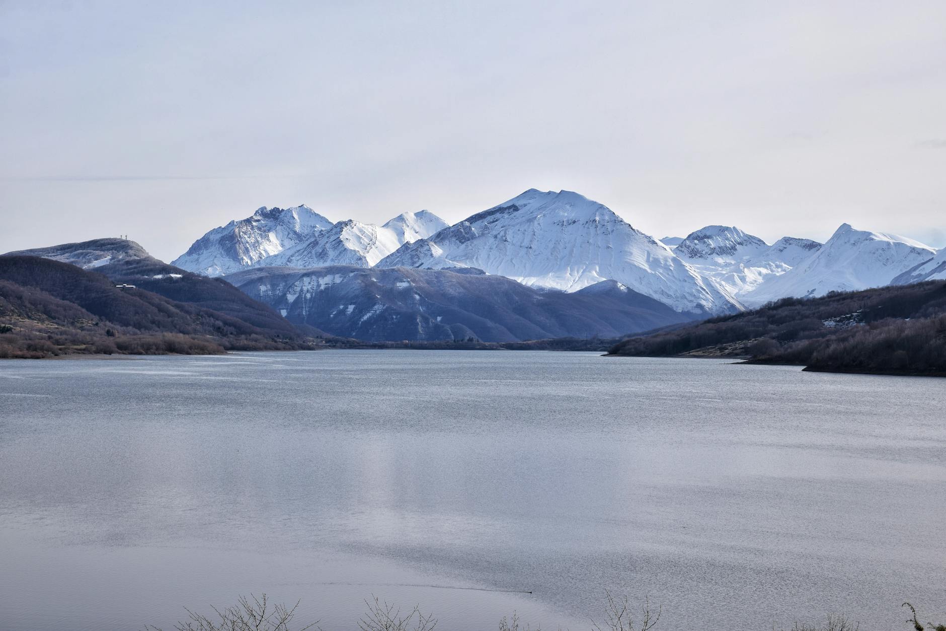 Captivating view of Lake Campotosto with snow-capped mountains in Abruzzo, Italy.