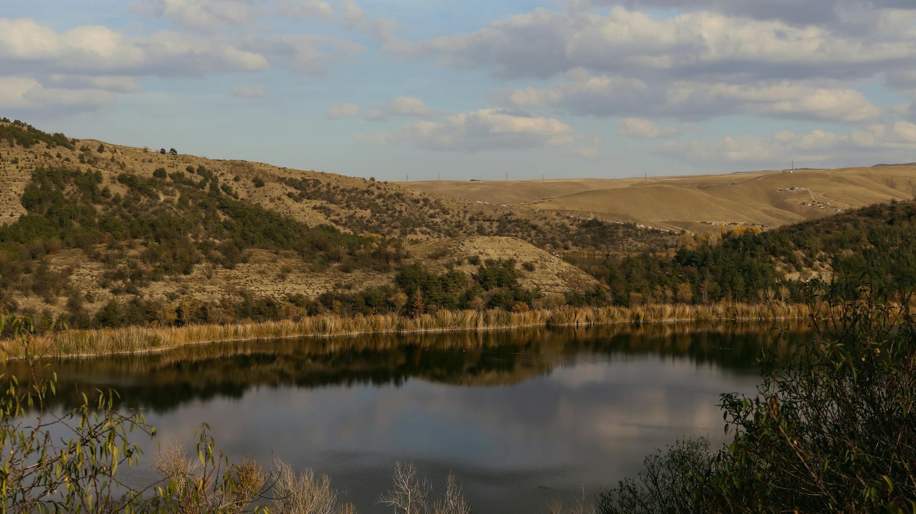 Picturesque view of a lake and hills under a partly cloudy sky in Ankara, Türkiye.