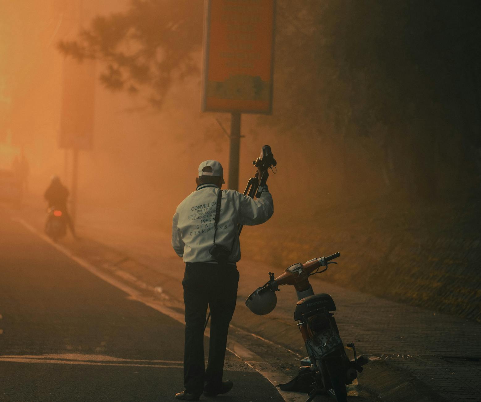 A photographer sets up his equipment on a misty street at dawn, capturing the quiet urban ambiance.