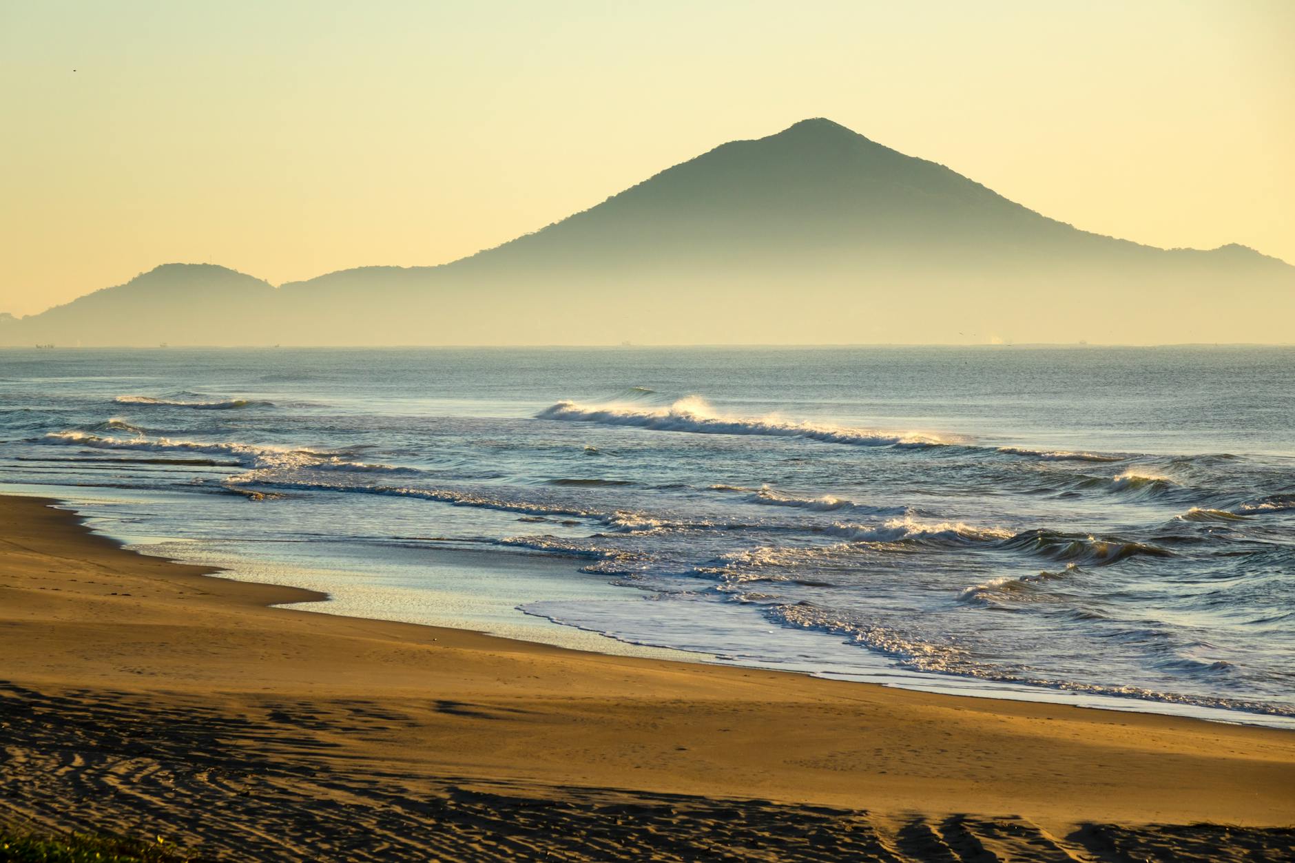 Tranquil beach scene at sunrise with misty mountains in Navegantes, Brazil.