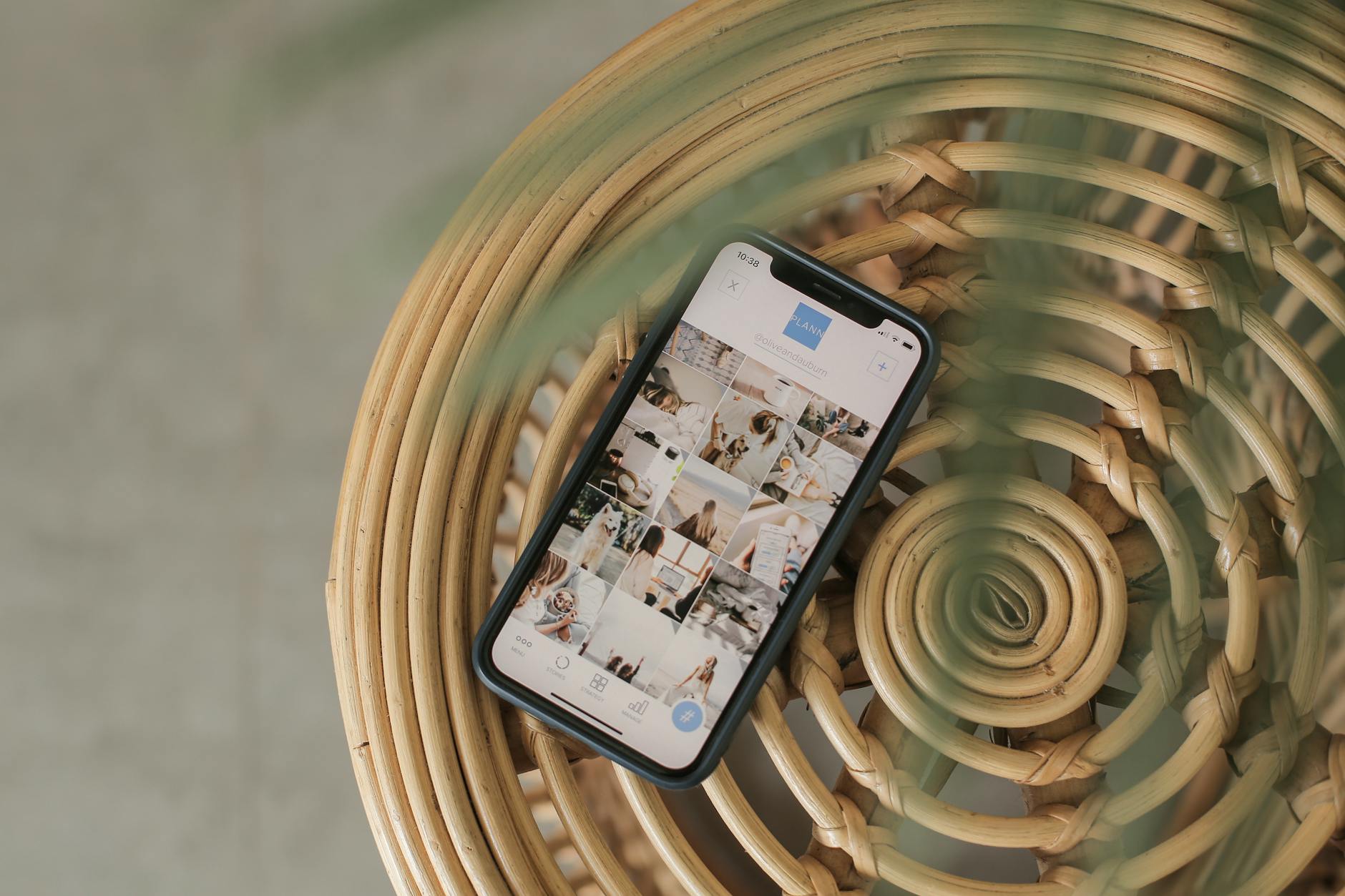 A smartphone displaying a social media app interface, placed on a wicker chair, creating a relaxed Bali vibe.