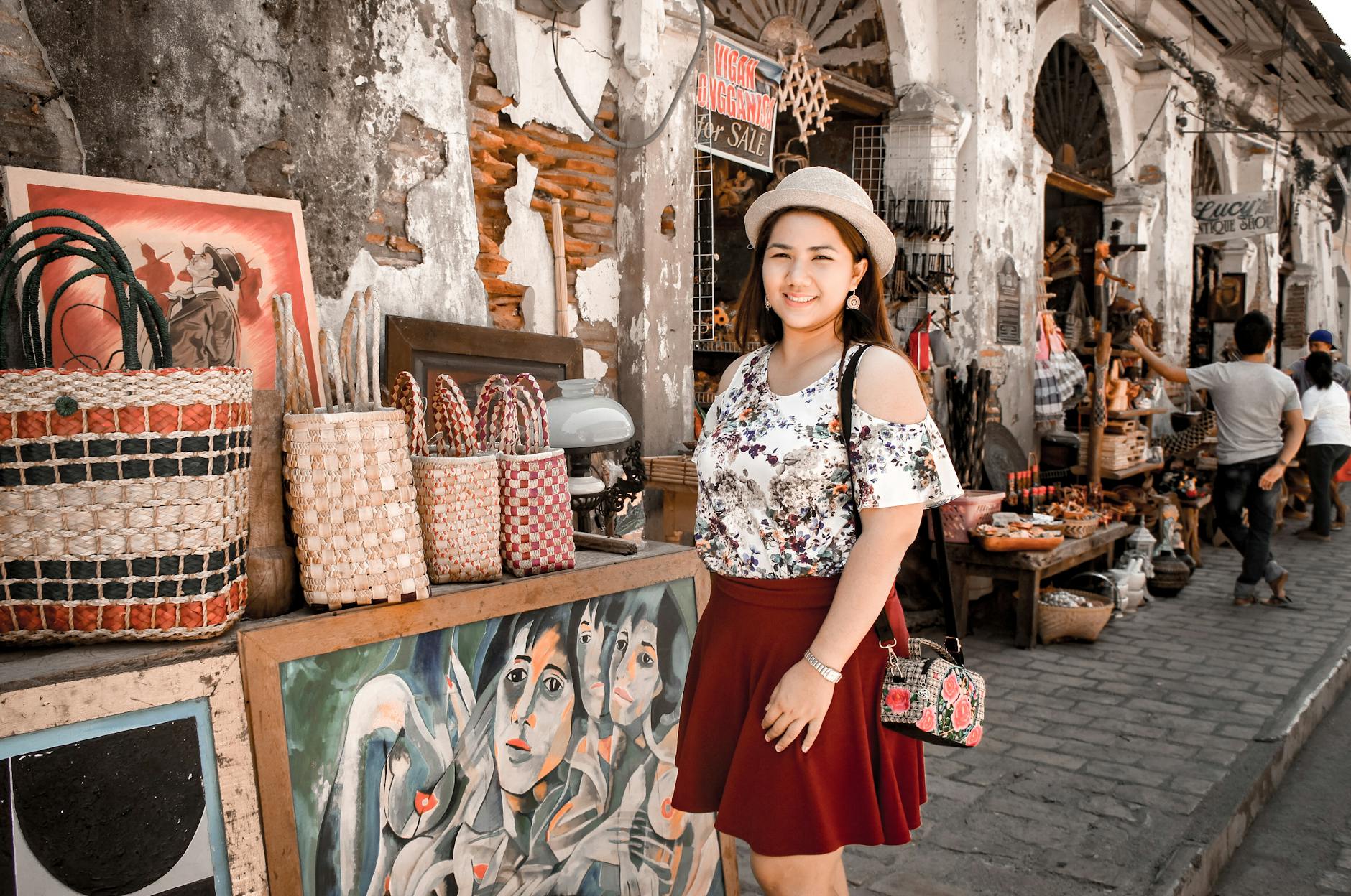 A fashionable tourist poses on Vigan City's quaint street market, showcasing local crafts and heritage.