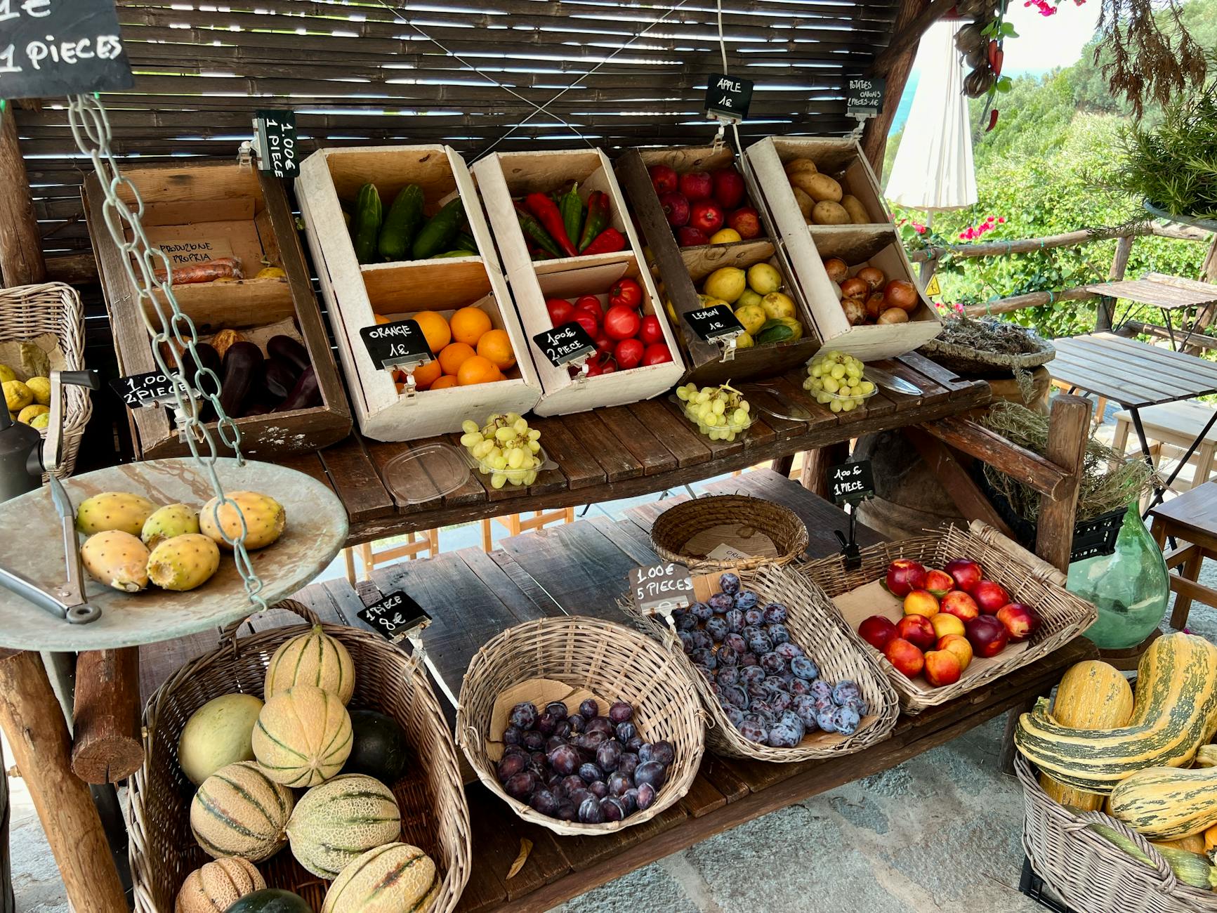 A rustic display of fresh fruits and vegetables at an outdoor market stall.