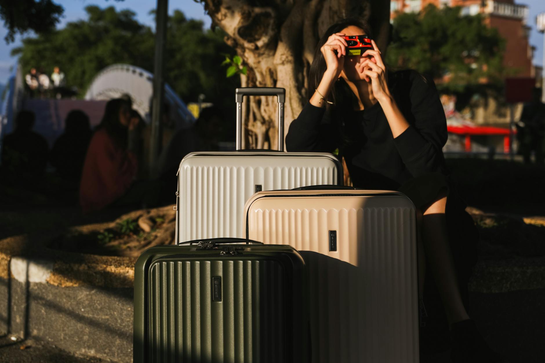 A woman captures moments with a vintage camera beside suitcases outdoors. Perfect for travel themes.