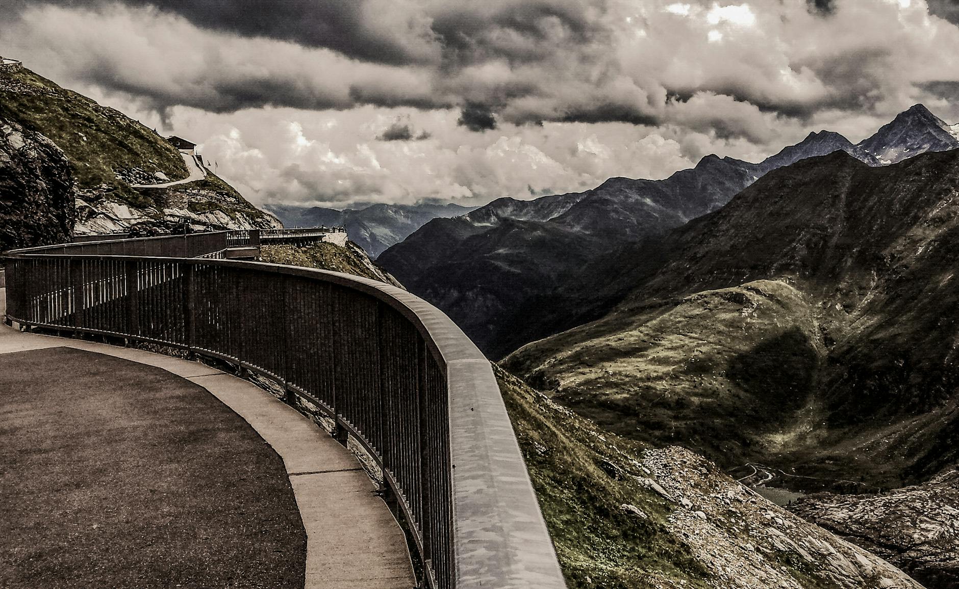Dramatic mountain road with metal railings in Krössenbach, Austria under stormy clouds.