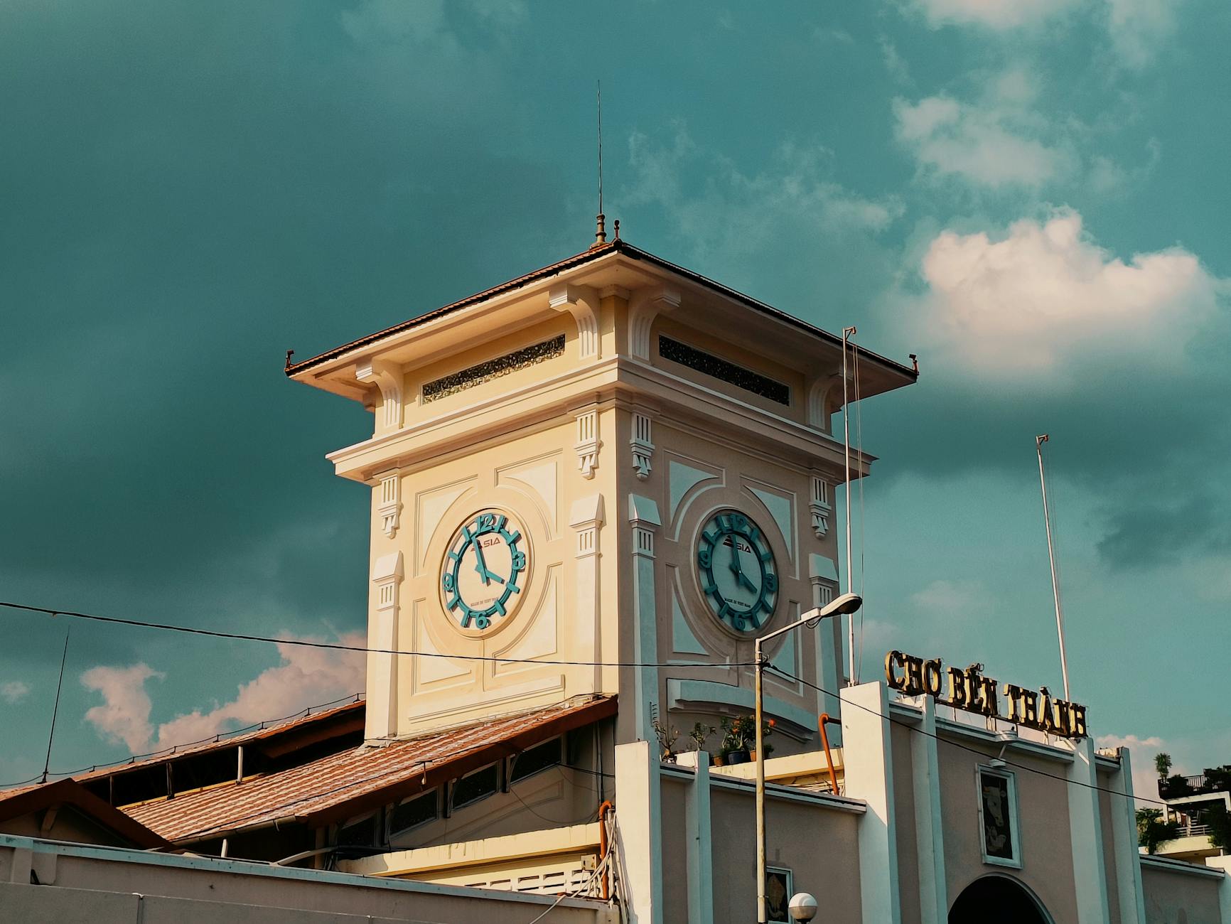 Architectural view of the Ben Thanh Market clock tower in Ho Chi Minh City under a vibrant sky.