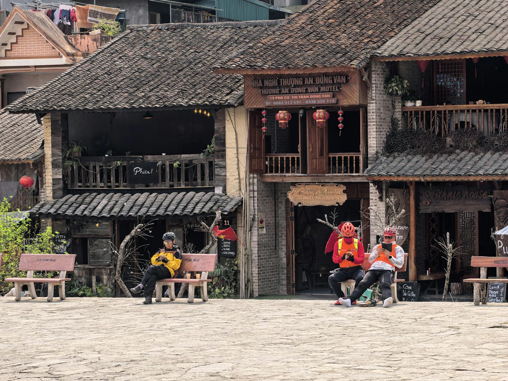People relaxing at a traditional Vietnamese plaza in Dong Van, surrounded by historic architecture.