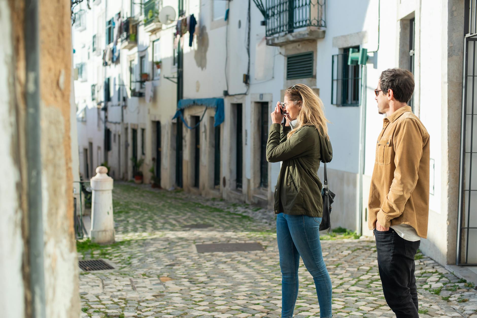 A couple exploring a quaint, cobblestone street and capturing the moment on camera. Perfect for travel themes.
