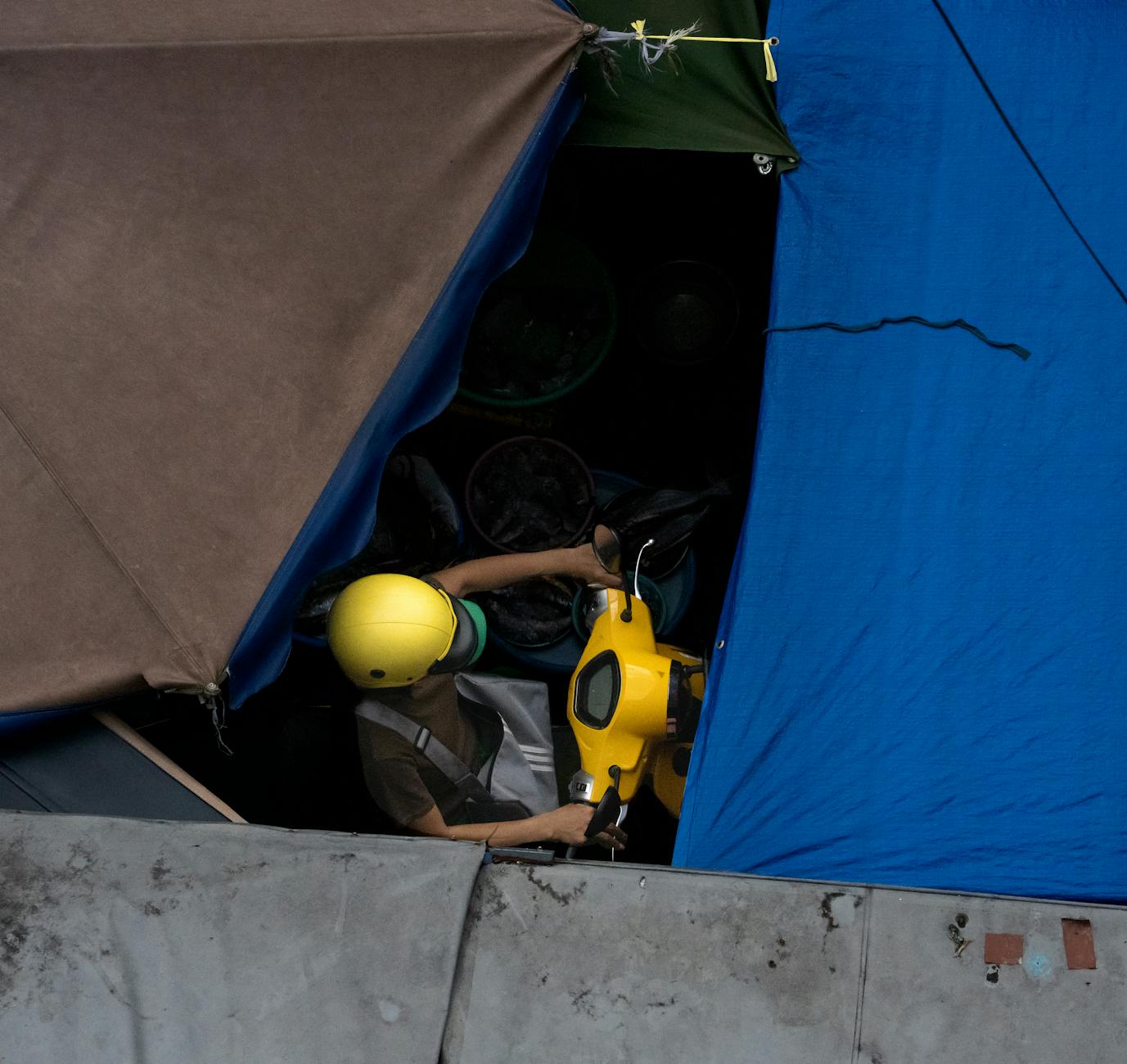 A top-down view captures vibrant market life in Vietnam with a yellow helmet rider.