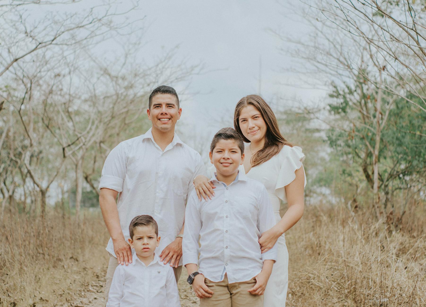 A joyful family poses together in a serene countryside setting, showcasing warmth and togetherness.