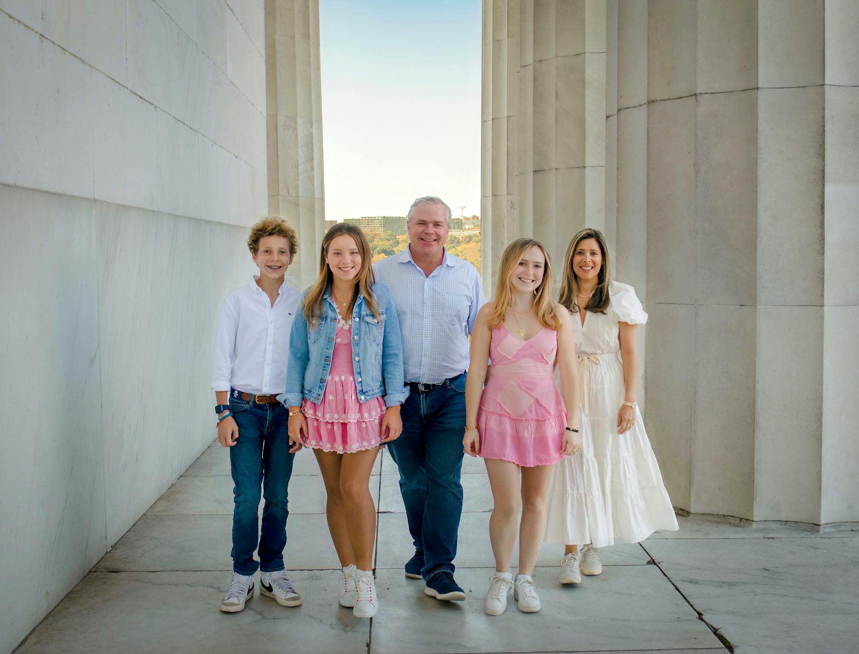 A happy family posing together outdoors at a monument, smiling in harmony.