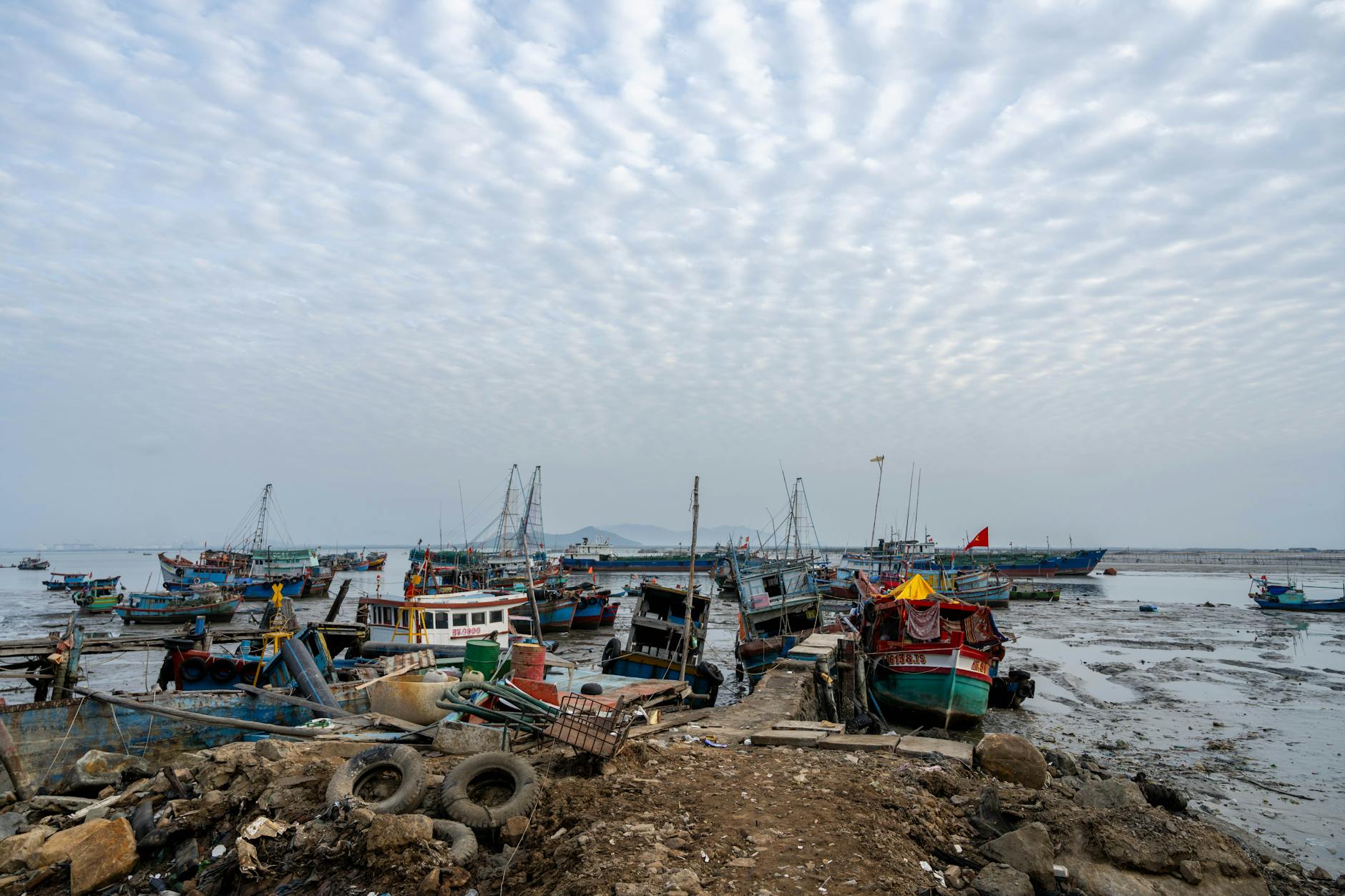 Colorful fishing boats docked on a cloudy day in Vũng Tàu, showcasing vibrant maritime life.