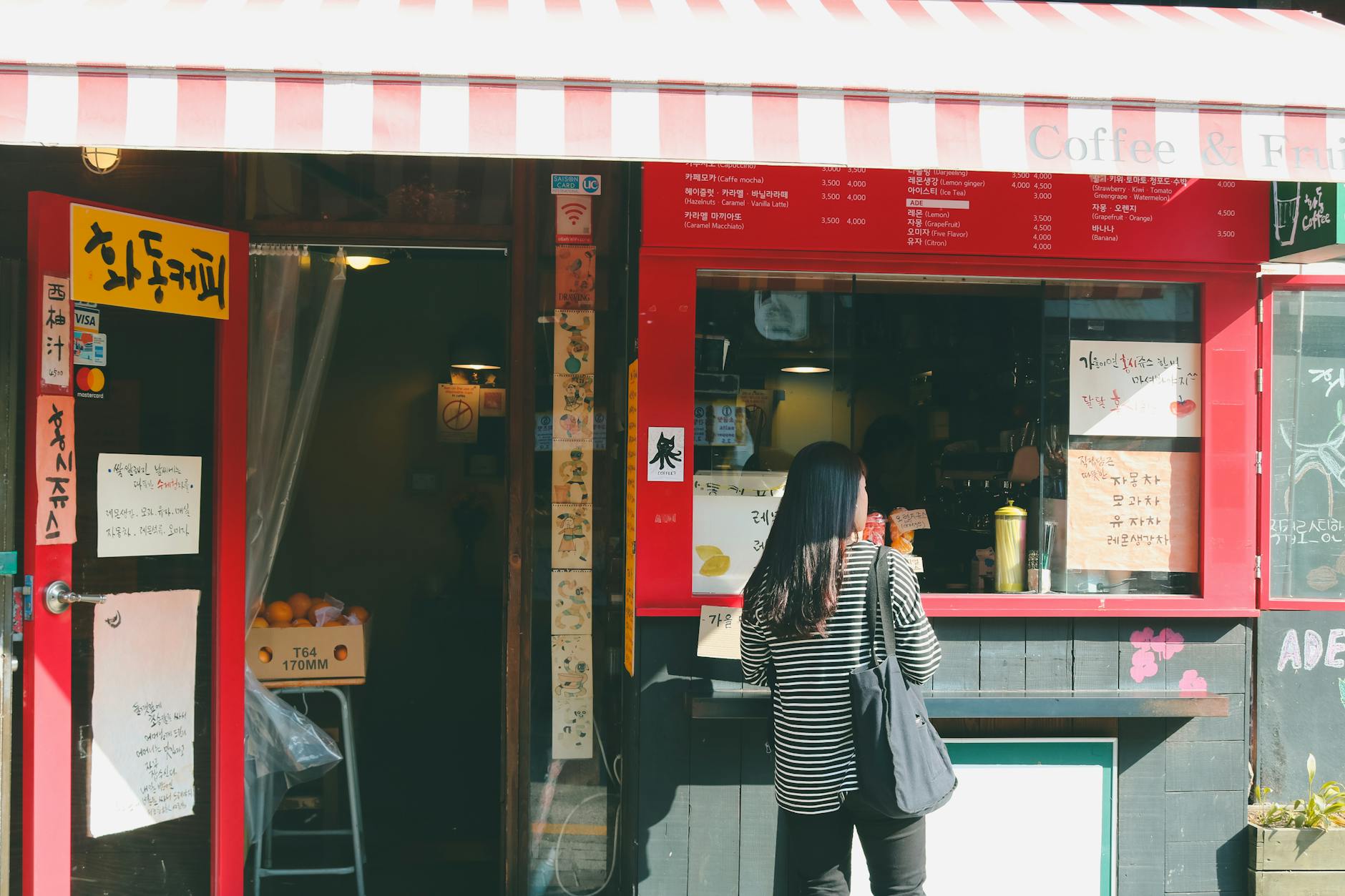 A quaint coffee shop with a striped awning in Seoul's Bukchon Hanok Village captures local charm.